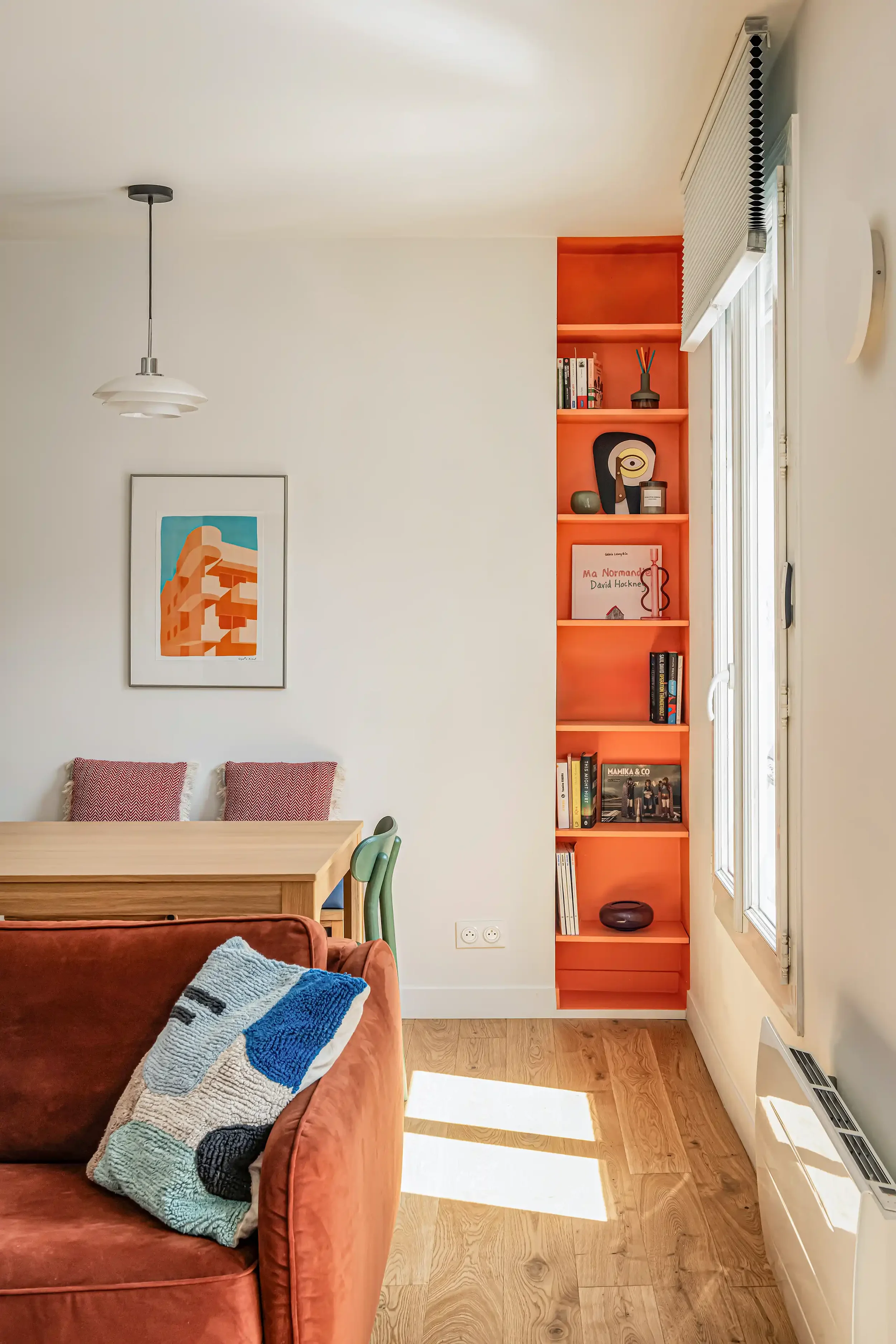 Vue d'ensemble d'une niche orange flashy accueillant une bibliothèque sur mesure près d'une table à manger.