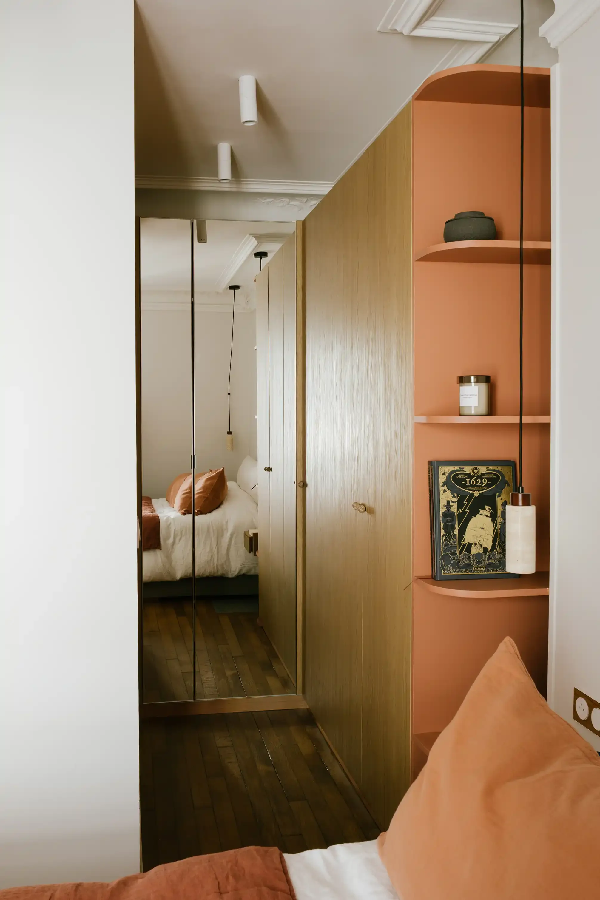 Grand dressing sur-mesure en bois clair intégrant un miroir vertical, installé dans une chambre d'un appartement de style bohème chic.