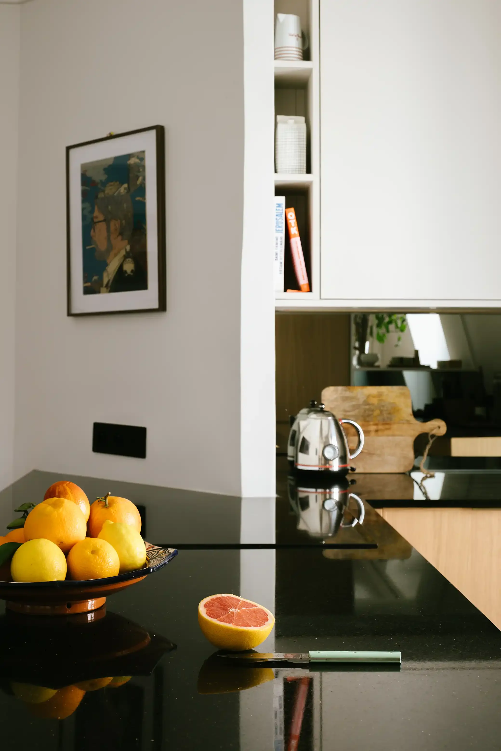 Gros plan sur un plan de travail en granit noir brillant dans une cuisine équipée moderne avec façades en bois et rangements sur mesure.