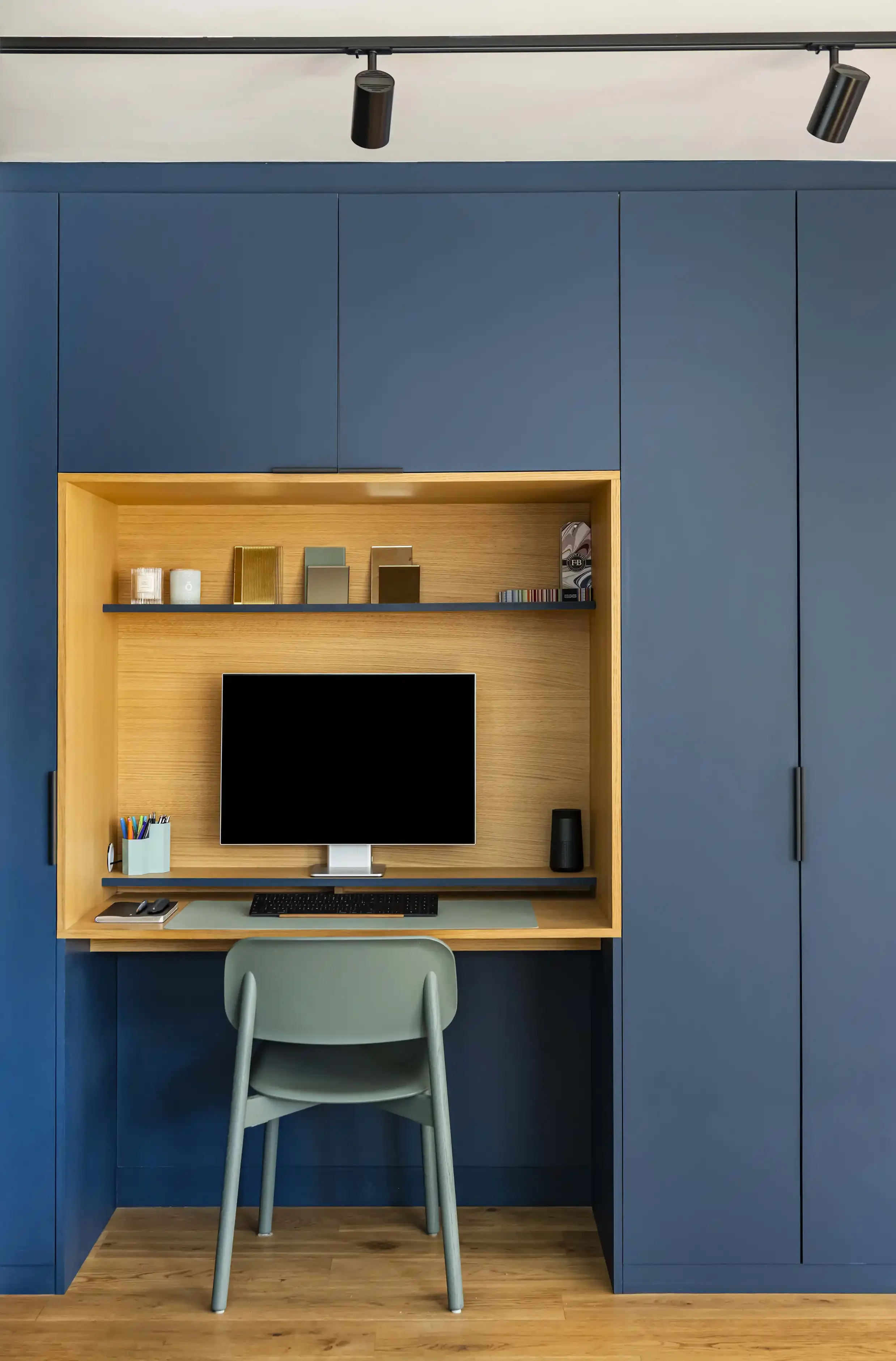 Coin bureau sur mesure intégré dans un meuble dressing bleu nuit avec niche en chêne clair et étagères de rangement.