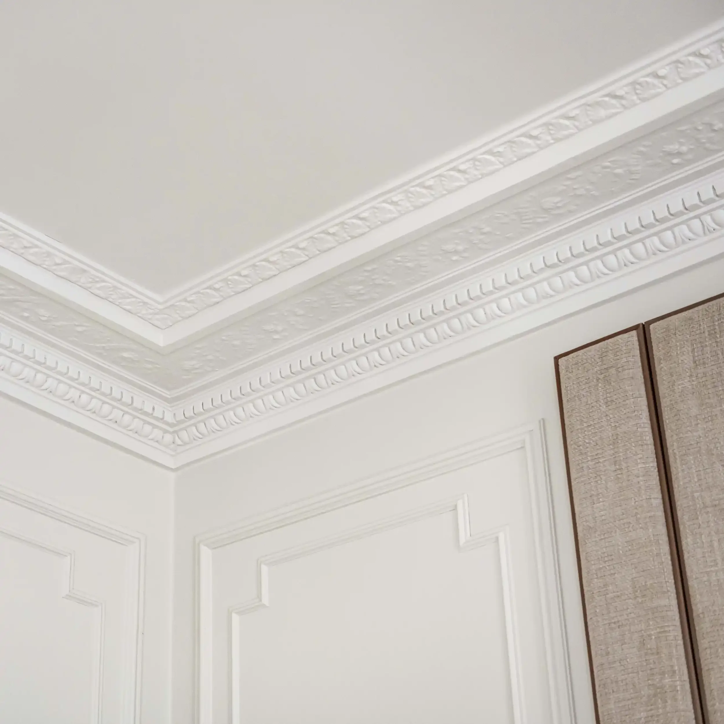 Détail d'angle de corniches de plafond richement ornées et moulures murales classiques en plâtre blanc.