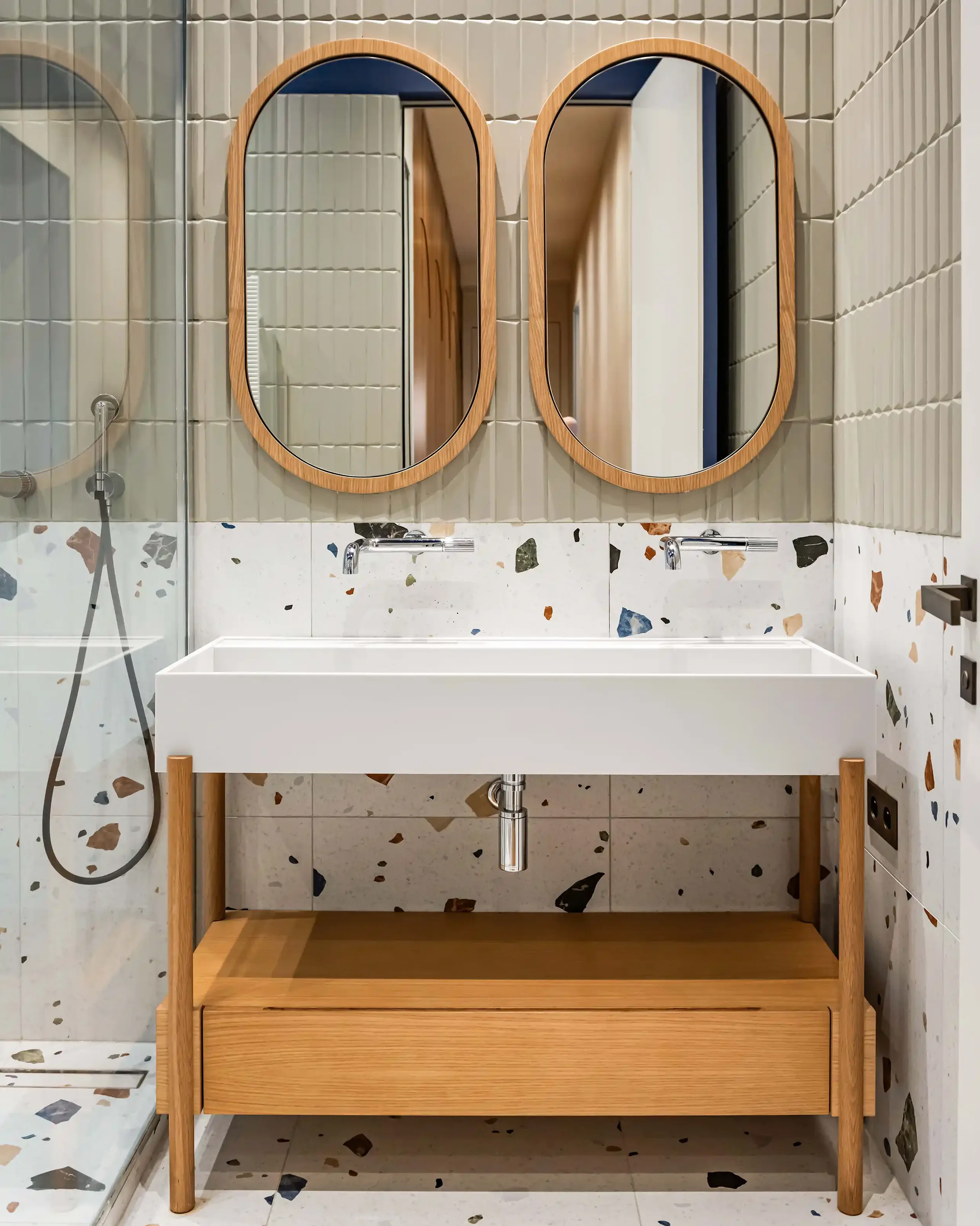 Meuble double vasque suspendu en bois et terrazzo dans une salle de bain moderne du 16ème arrondissement.