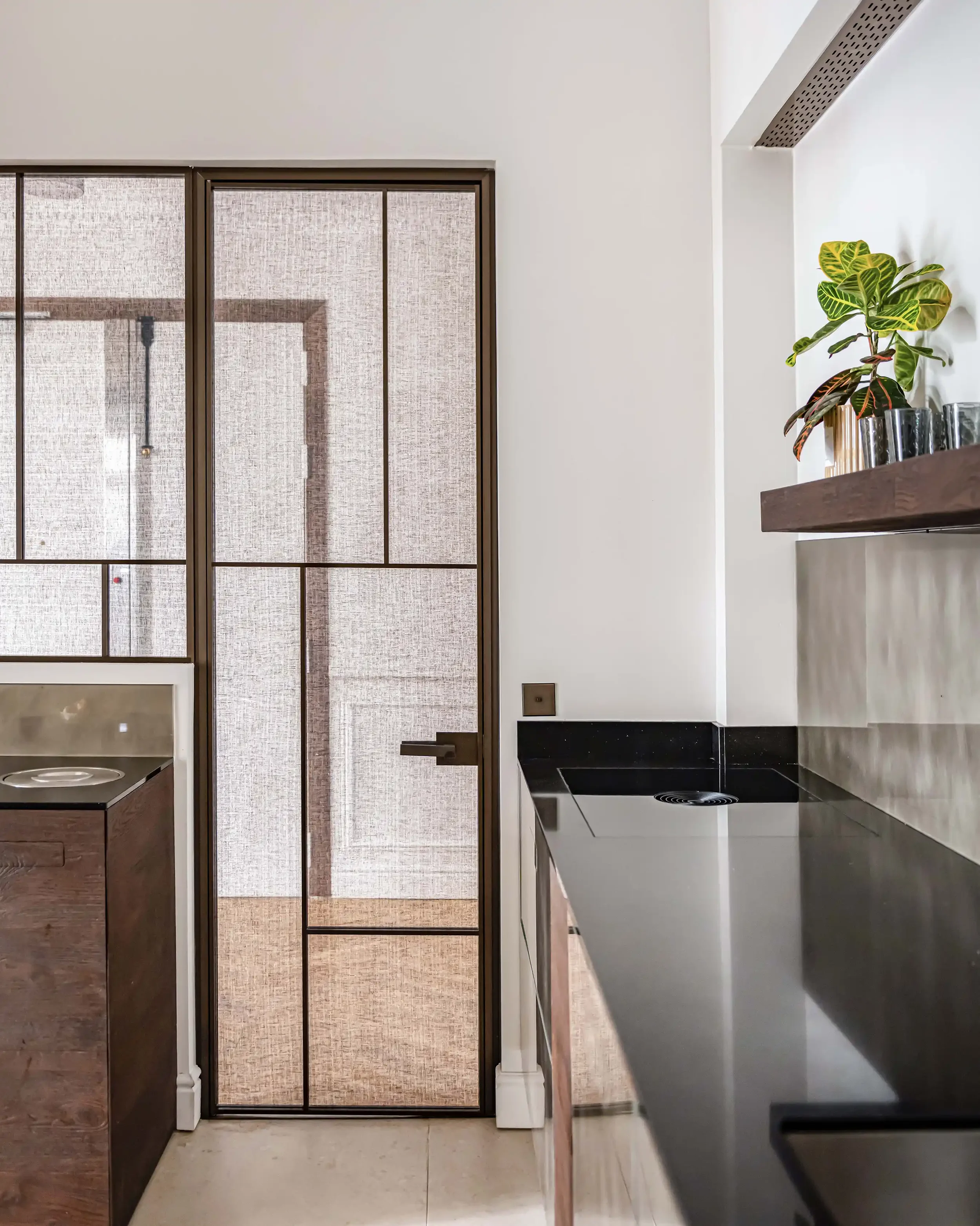 Verrière de cuisine moderne en métal bronze avec vitrage texturé séparant la cuisine et l'entrée de l'appartement.
