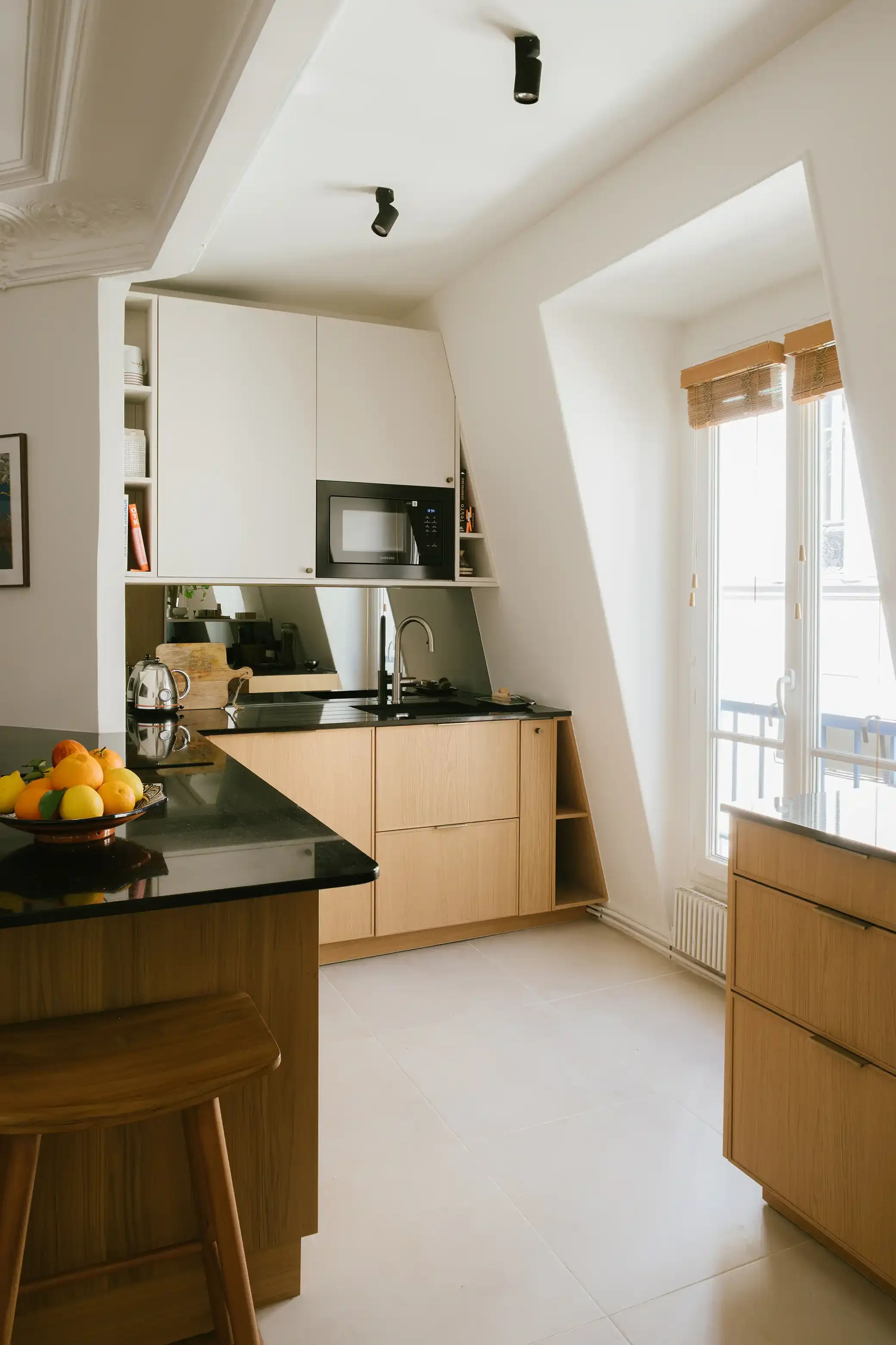 Aménagement d'une cuisine sous les combles avec meubles blancs et bois, optimisation d'espace sous pente et étagères sur-mesure.