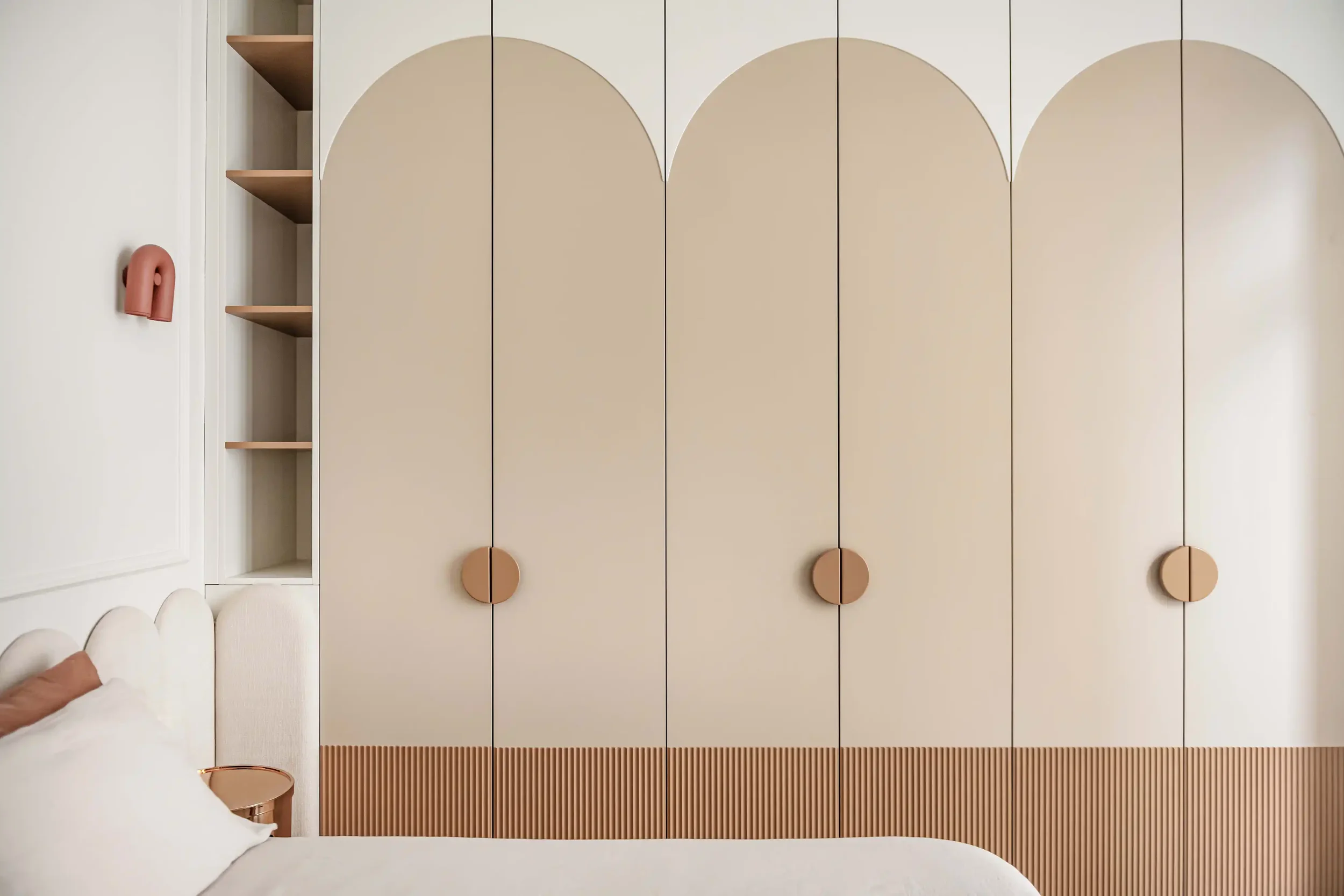 Armoire de chambre haut de gamme beige et bois cannelé avec design en arche et poignées demi-lune.
