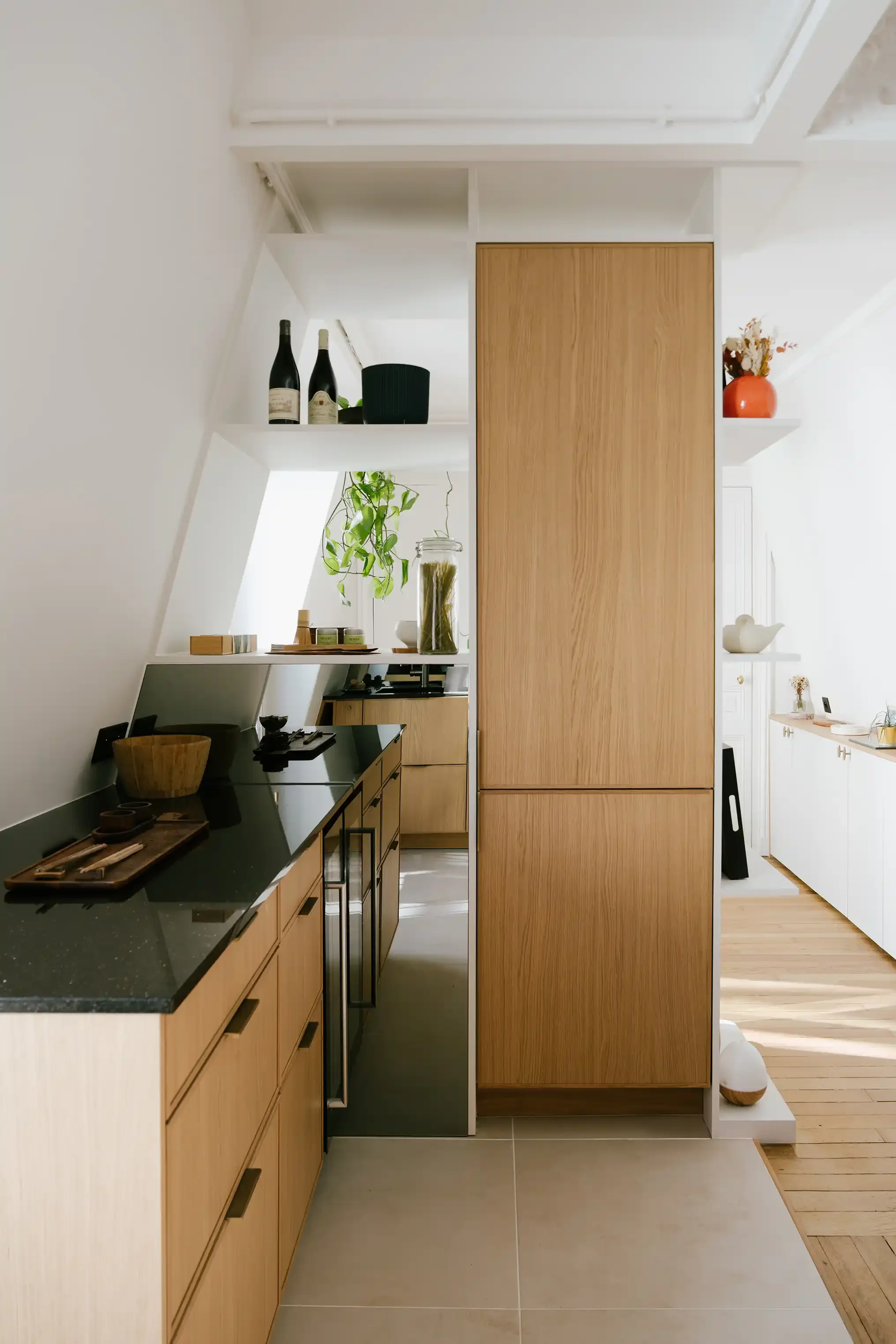 Cuisine moderne en bois de chêne avec plan de travail en granit noir et électroménager intégré, aménagement intérieur parisien.