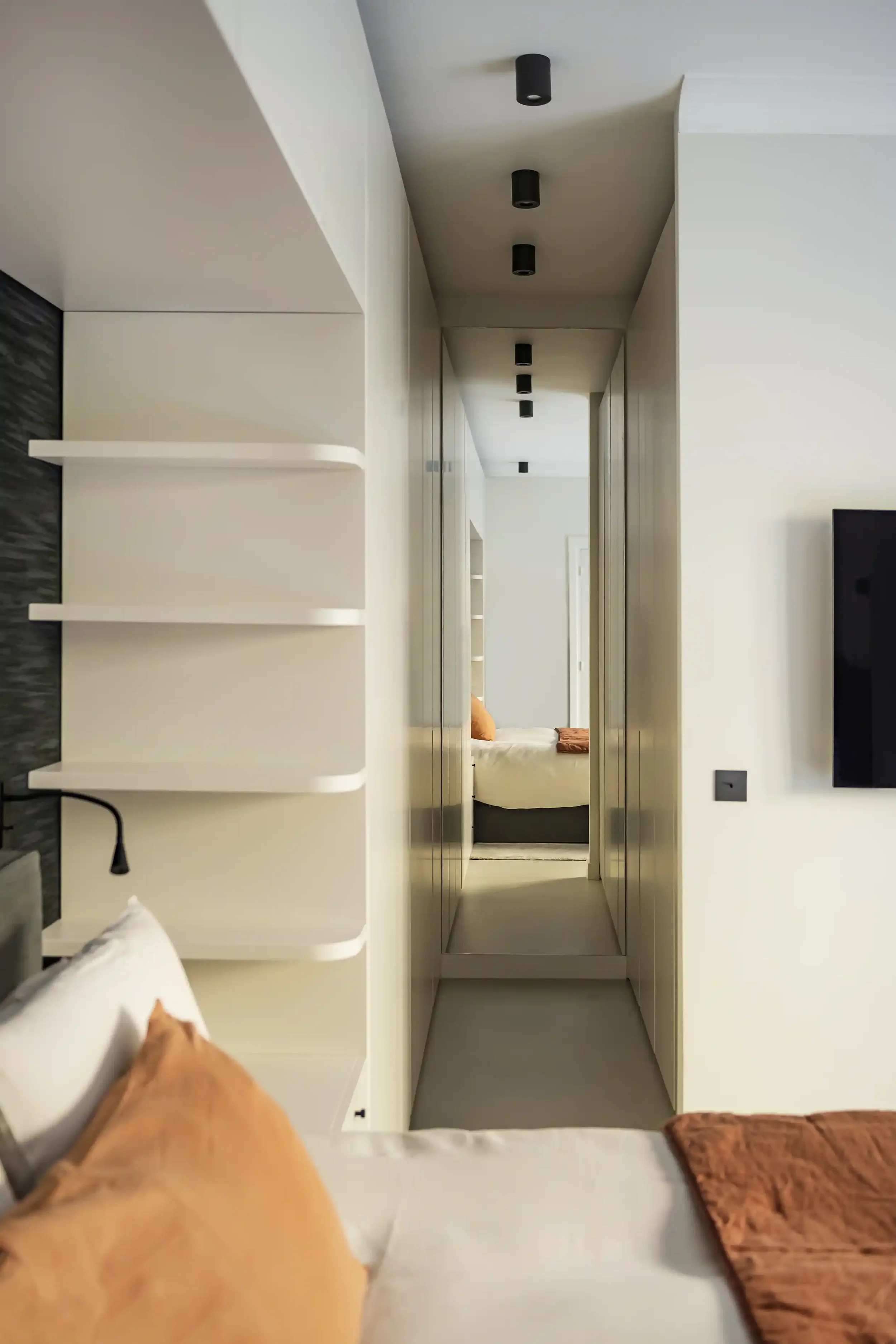 Aménagement de chambre parentale avec vue sur un grand dressing sur-mesure minimaliste et porte coulissante blanche.