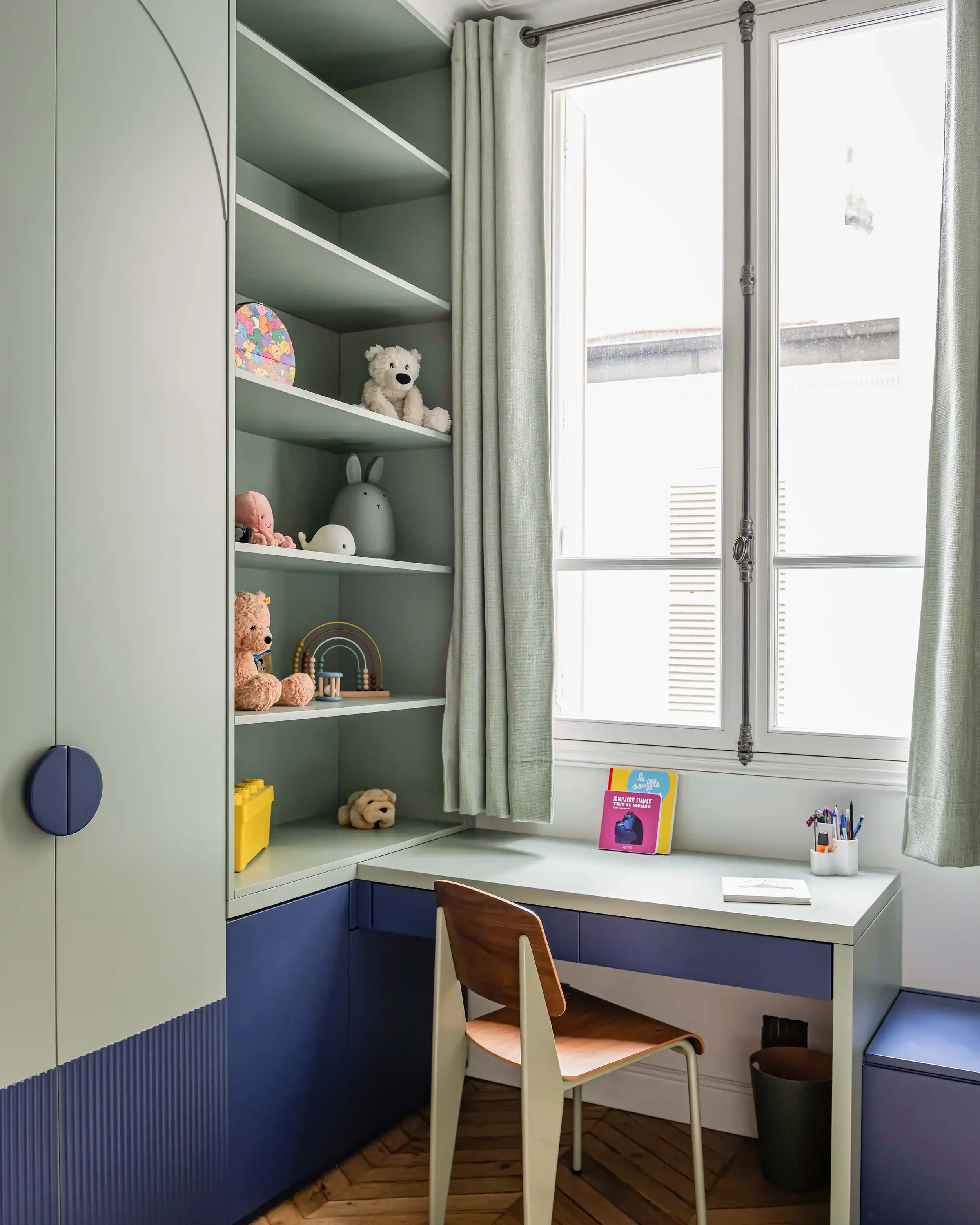 Espace de travail enfant avec bureau sur mesure vert sauge et étagères minimalistes dans le 16ème arrondissement.