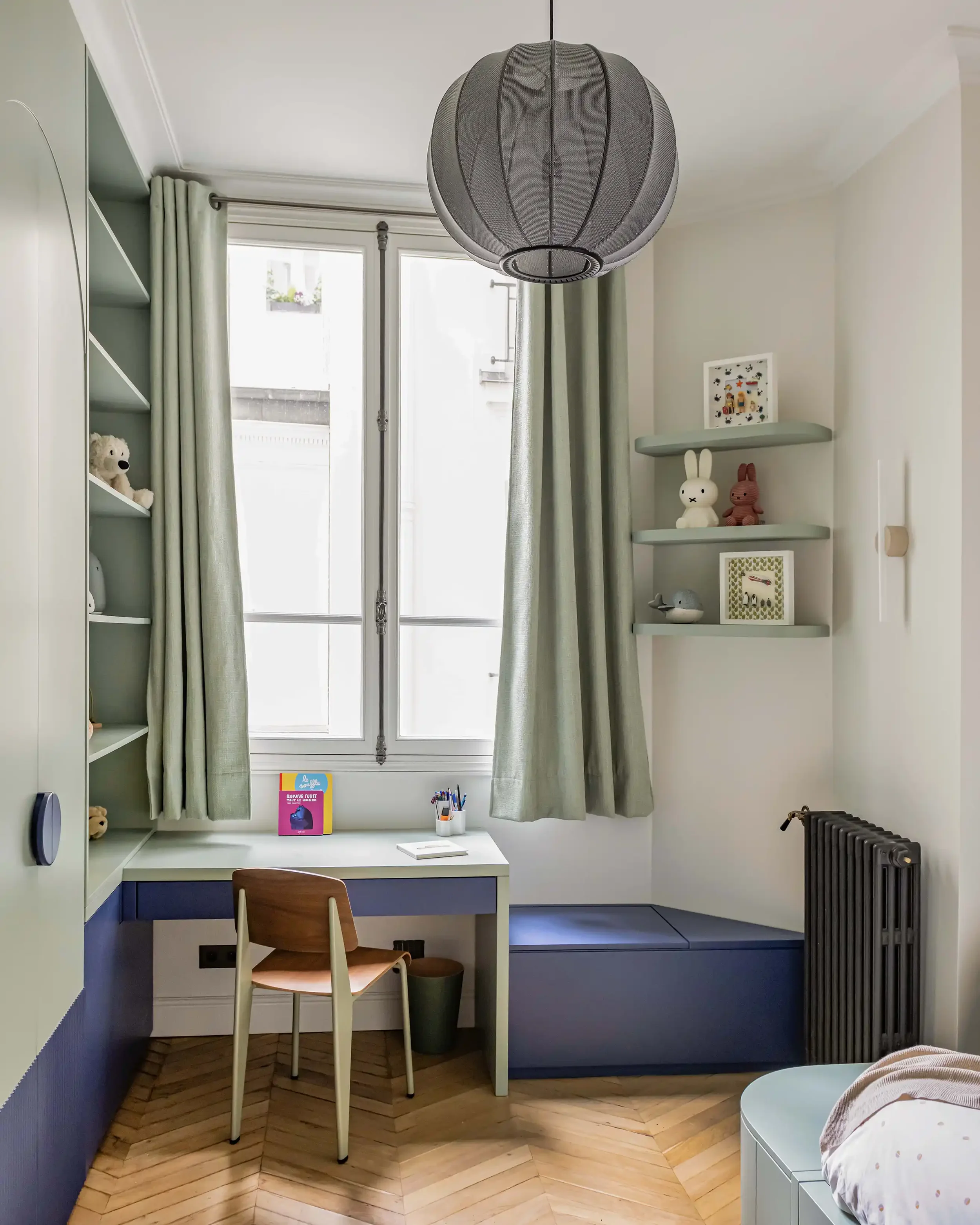 Vue d'ensemble d'une chambre d'enfant avec bureau intégré bleu, sol en parquet point de Hongrie et moulures.
