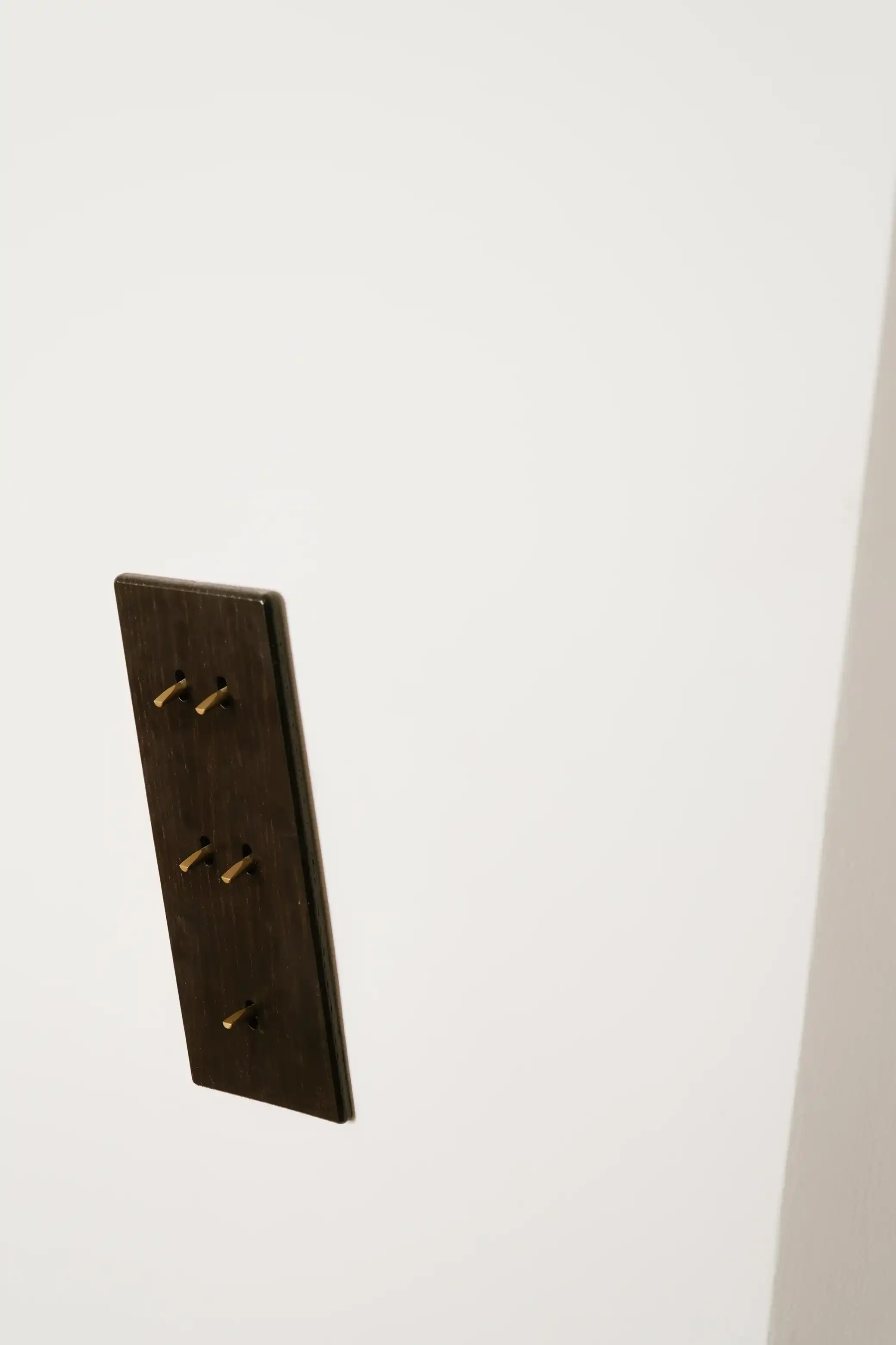Zoom sur un interrupteur haut de gamme à leviers dorés sur une plaque en bois sombre, accessoire de décoration minimaliste et luxueux.
