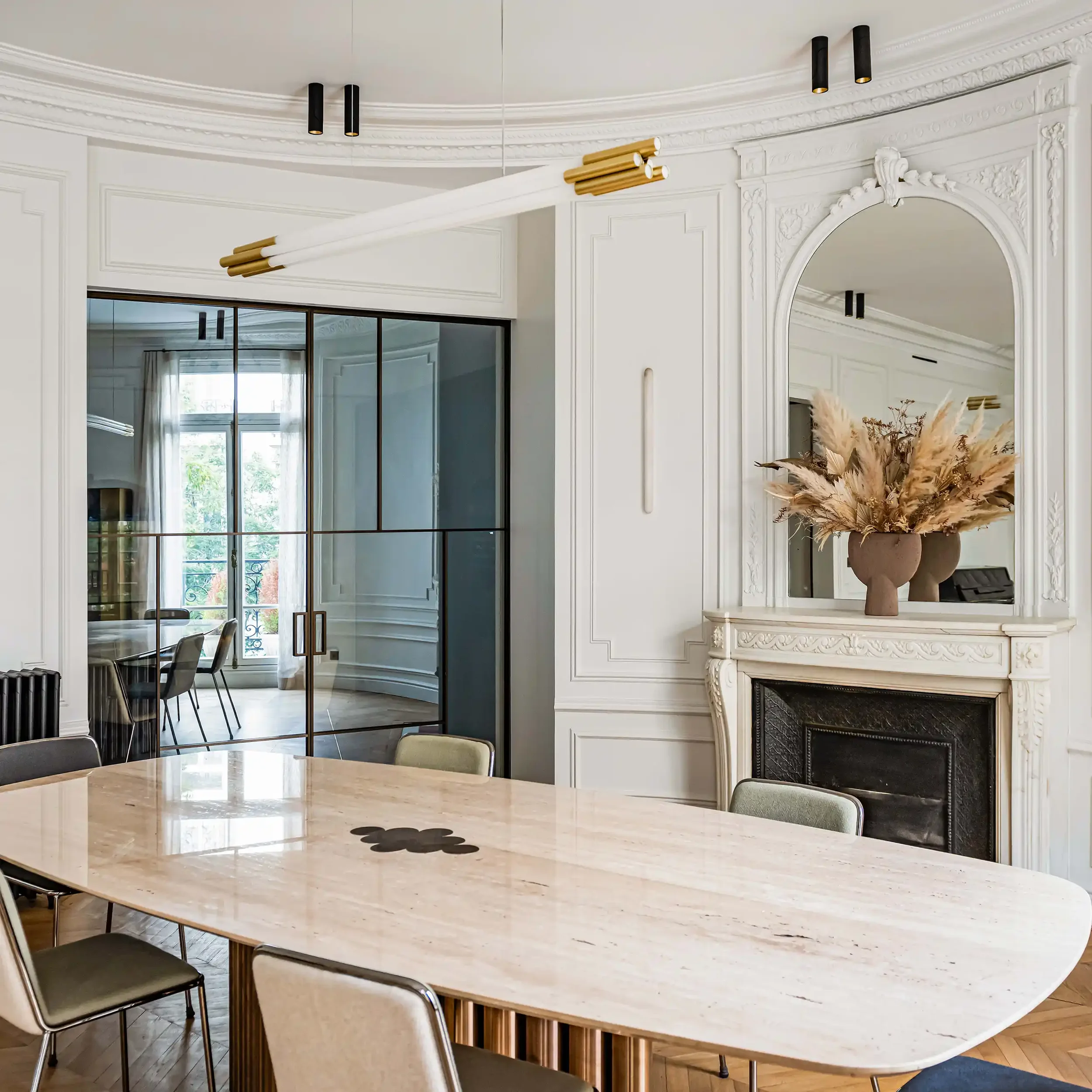Intérieur parisien prestigieux avec table en travertin, luminaires design et grandes portes vitrées.