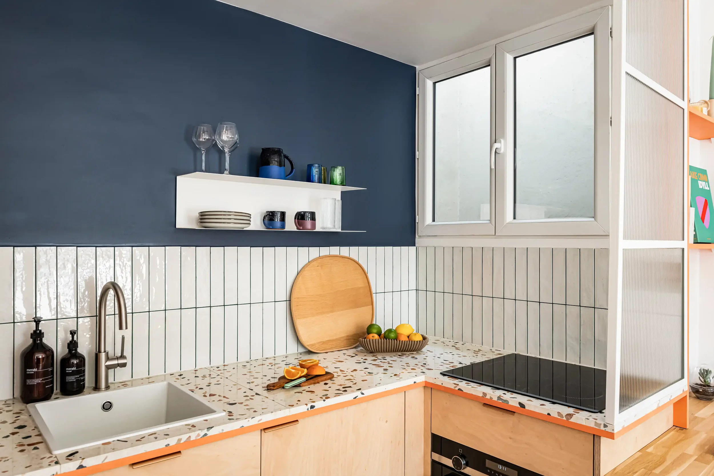 Détail d'un évier sous plan intégré dans un plan de travail en terrazzo blanc avec carrelage zellige en arrière-plan.