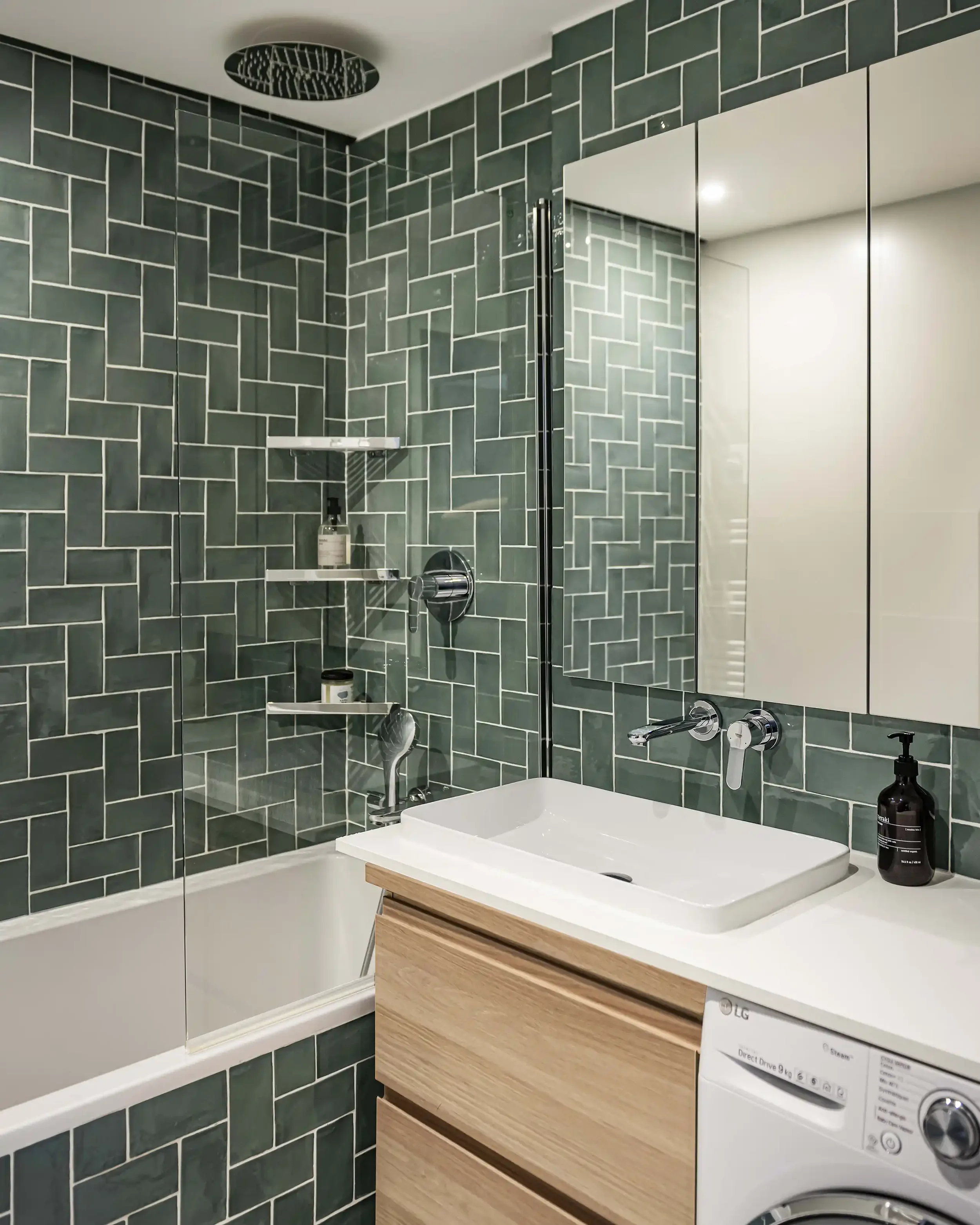Salle de bain moderne avec carrelage mural vert sauge posé à bâtons rompus et robinetterie noire.