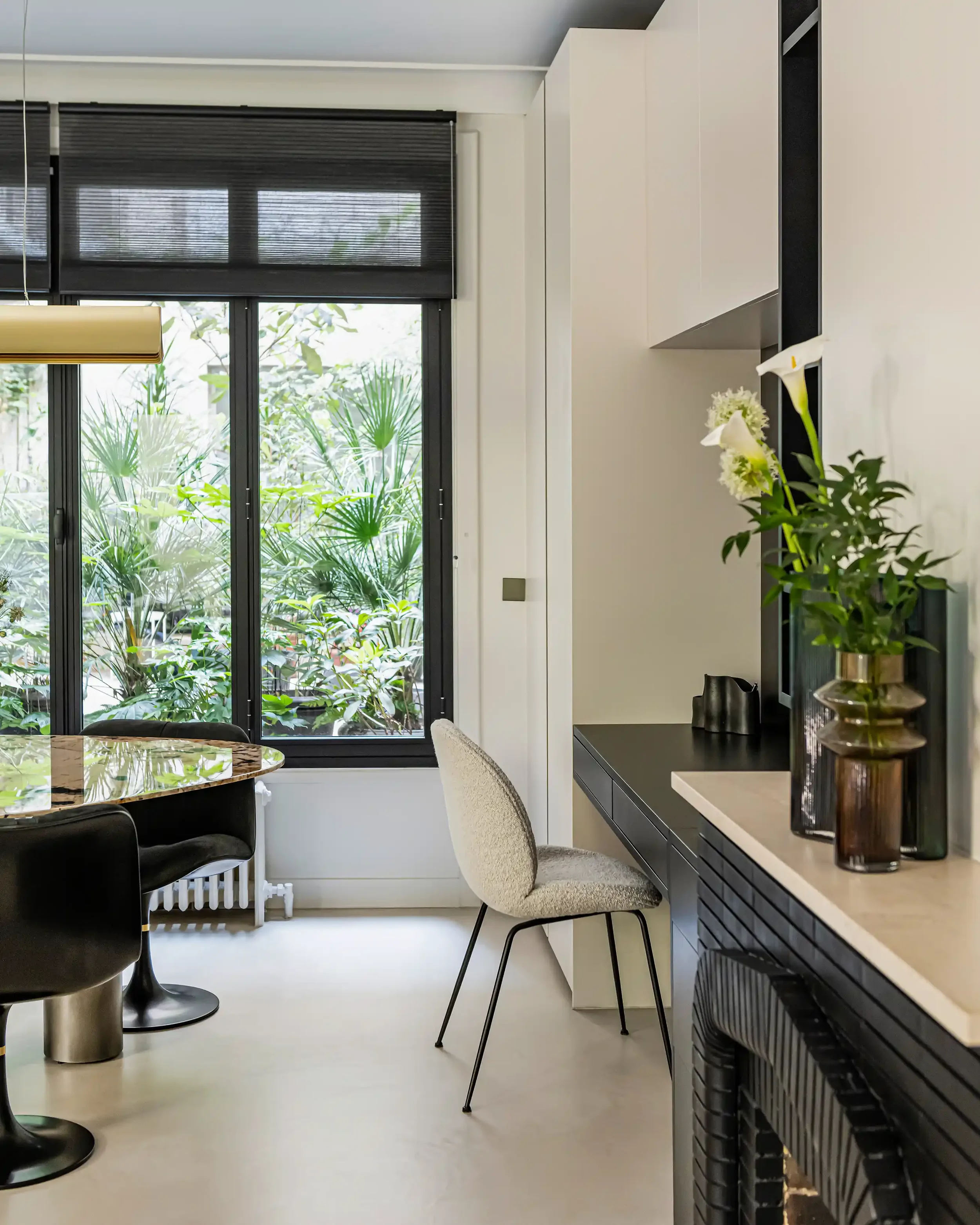 Coin bureau sur-mesure intégré face à une grande fenêtre donnant sur un jardin intérieur végétalisé à Paris.