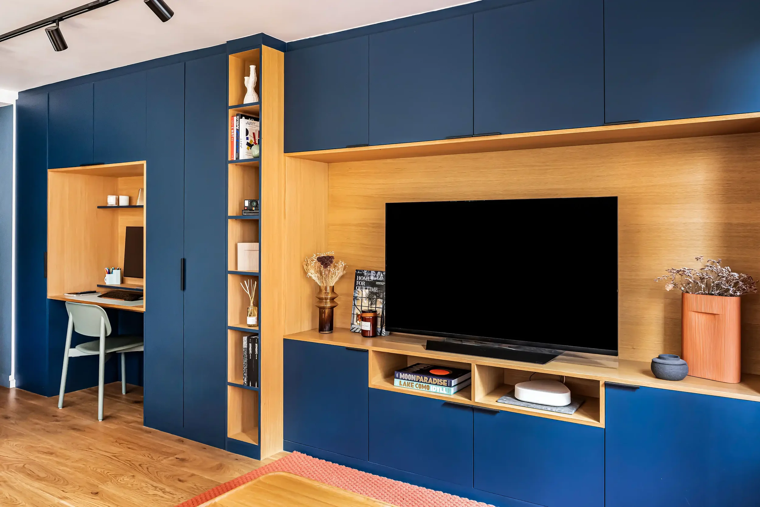 Meuble TV et bibliothèque sur mesure en bleu profond et bois clair optimisant le mur du salon.