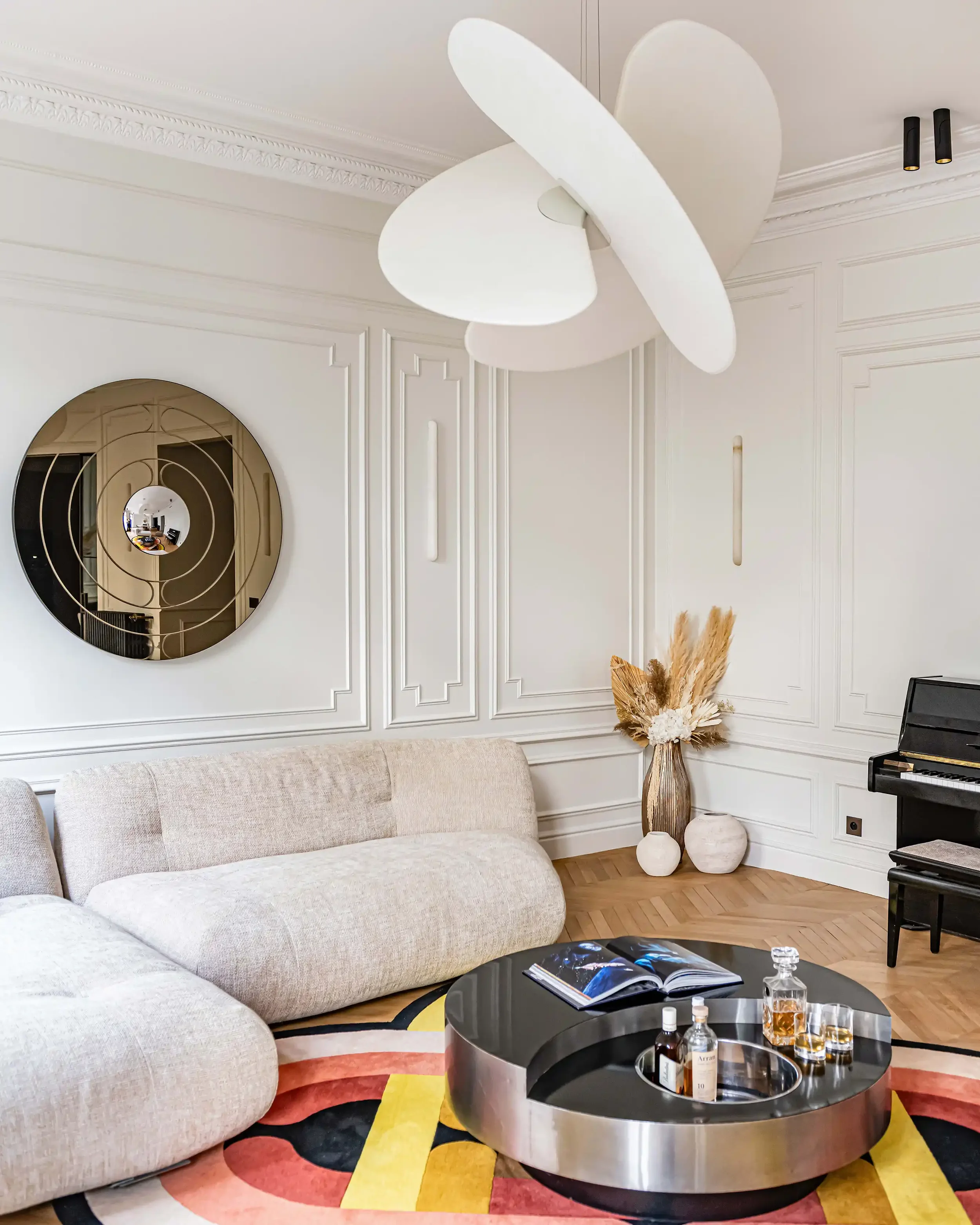 Salon de luxe à Paris avec canapé d'angle en tissu bouclé blanc, table basse design et moulures murales.