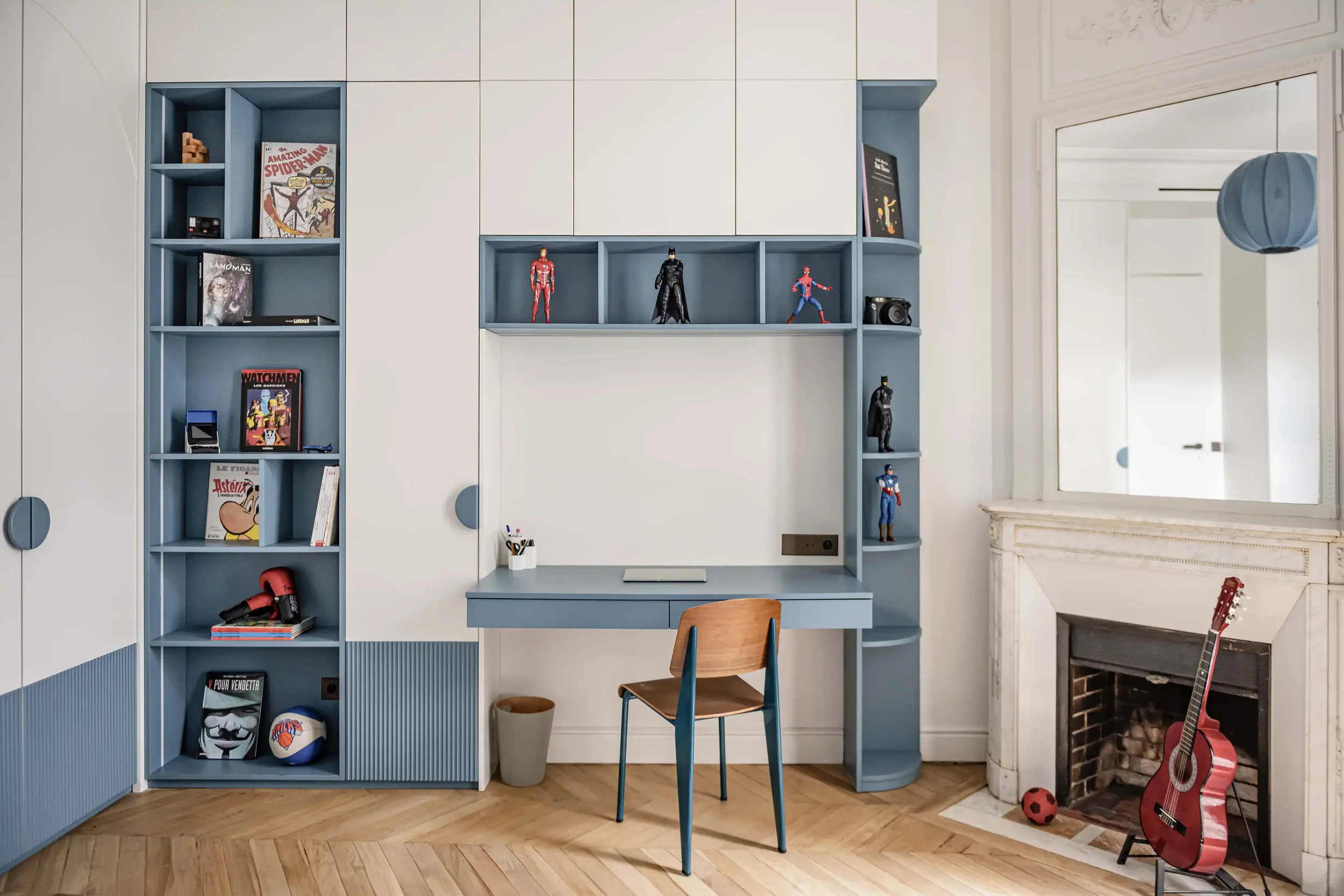 Bureau pour enfant intégré dans un grand meuble de rangement blanc et bleu sur mesure avec détails cannelés.
