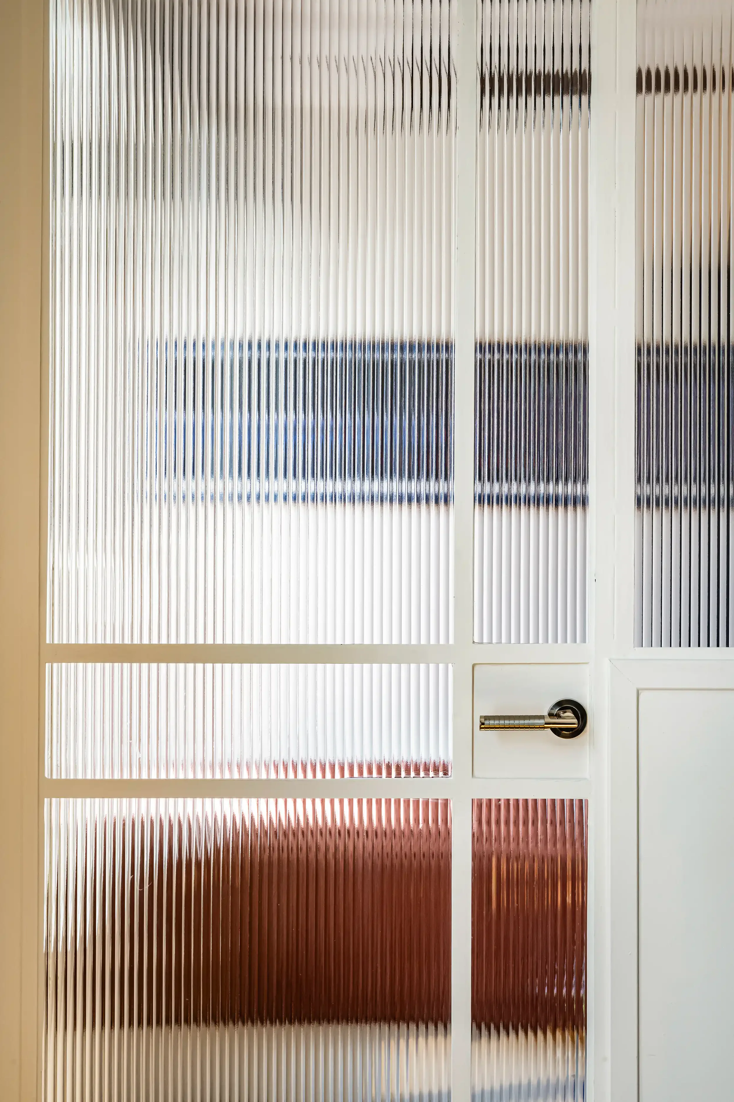 Porte vitrée avec cadre en bois et verre flûté servant de séparation élégante pour une chambre.