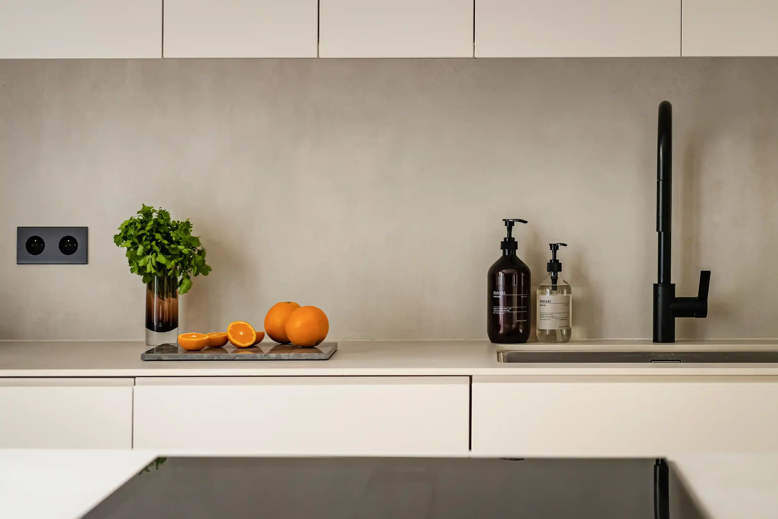 Zoom sur un îlot de cuisine avec plaque à induction noire et plan de travail fin en matériau compact blanc.