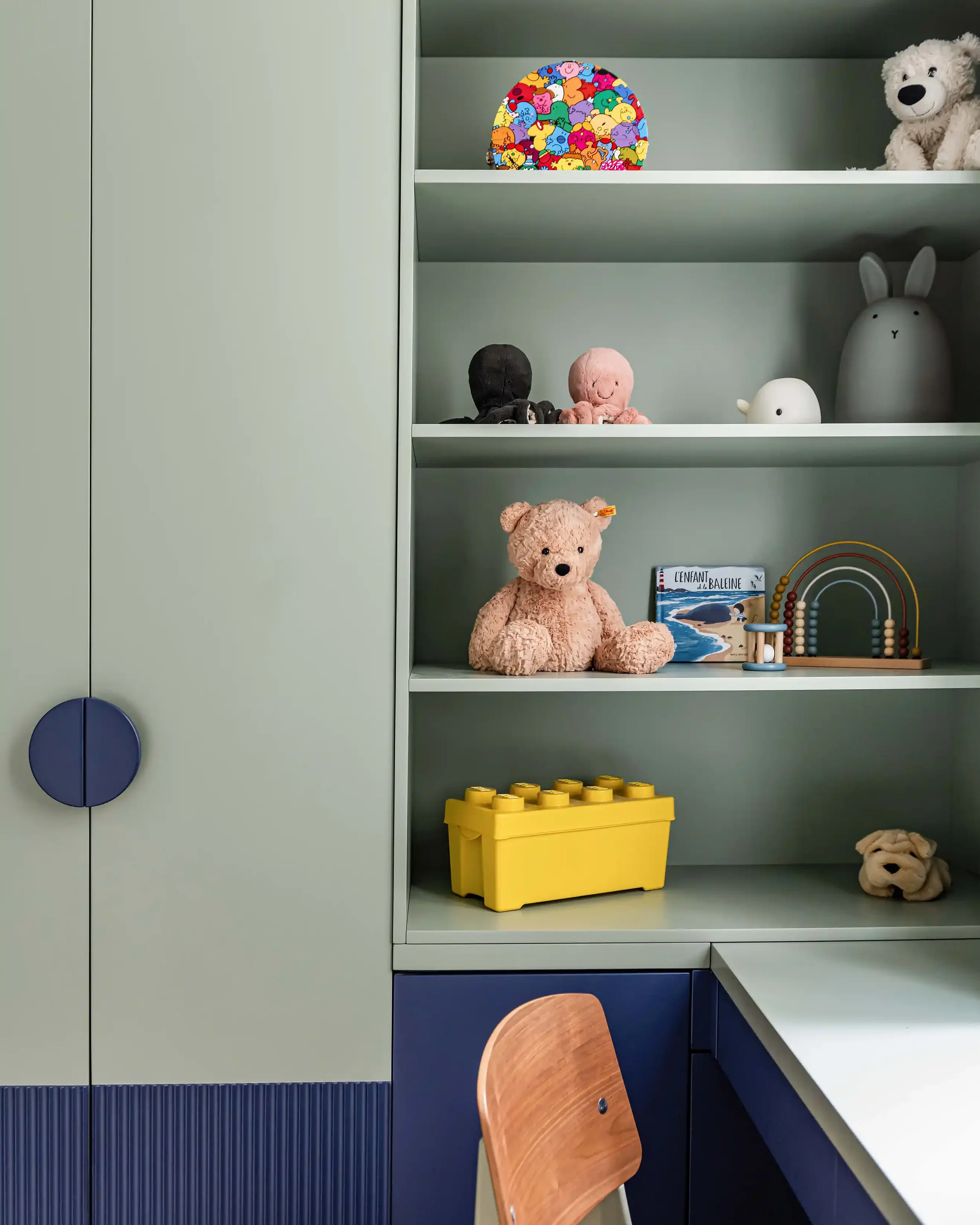 Détail d'un meuble de rangement sur mesure vert sauge et bleu pour chambre d'enfant.