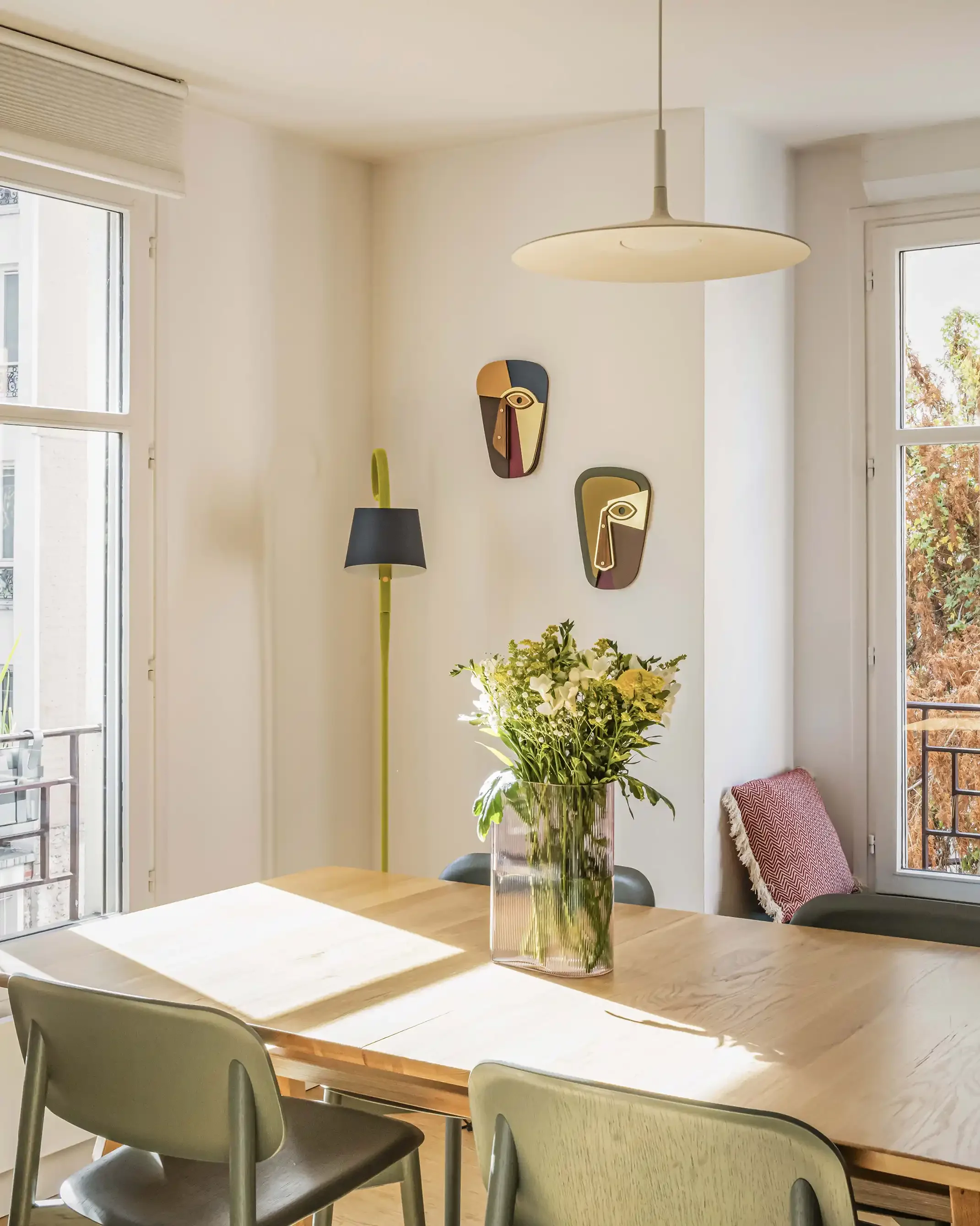 Salle à manger lumineuse style scandinave avec table en bois, chaises design et tapis texturé sous une lumière naturelle.