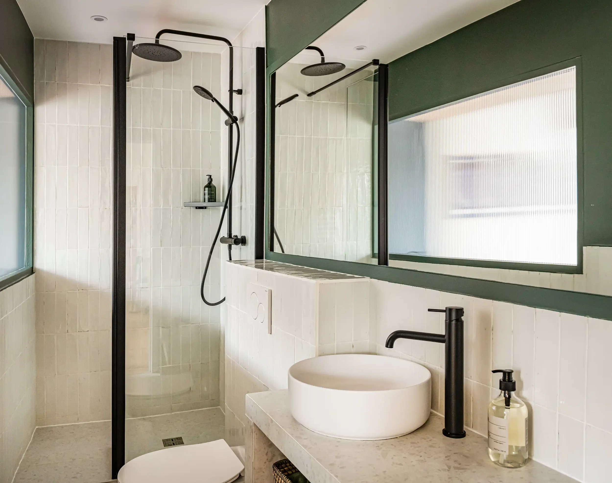 Salle de bain contemporaine avec murs en zellige blanc brillant et colonne de douche noir mat.