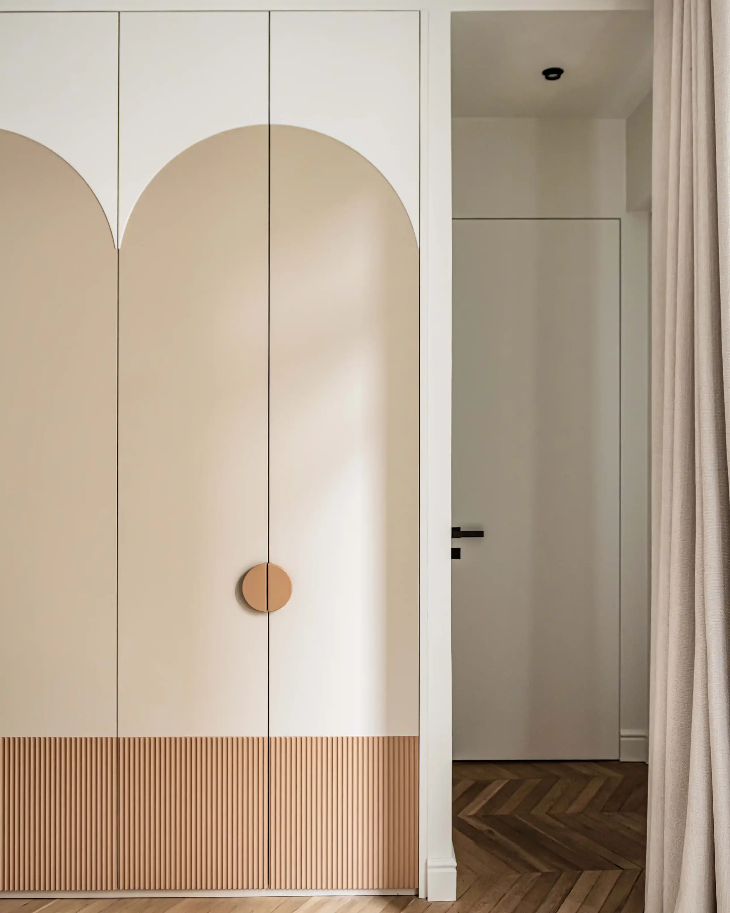 Détail de menuiserie personnalisée avec finitions texturées verticales et poignée circulaire en bois massif.