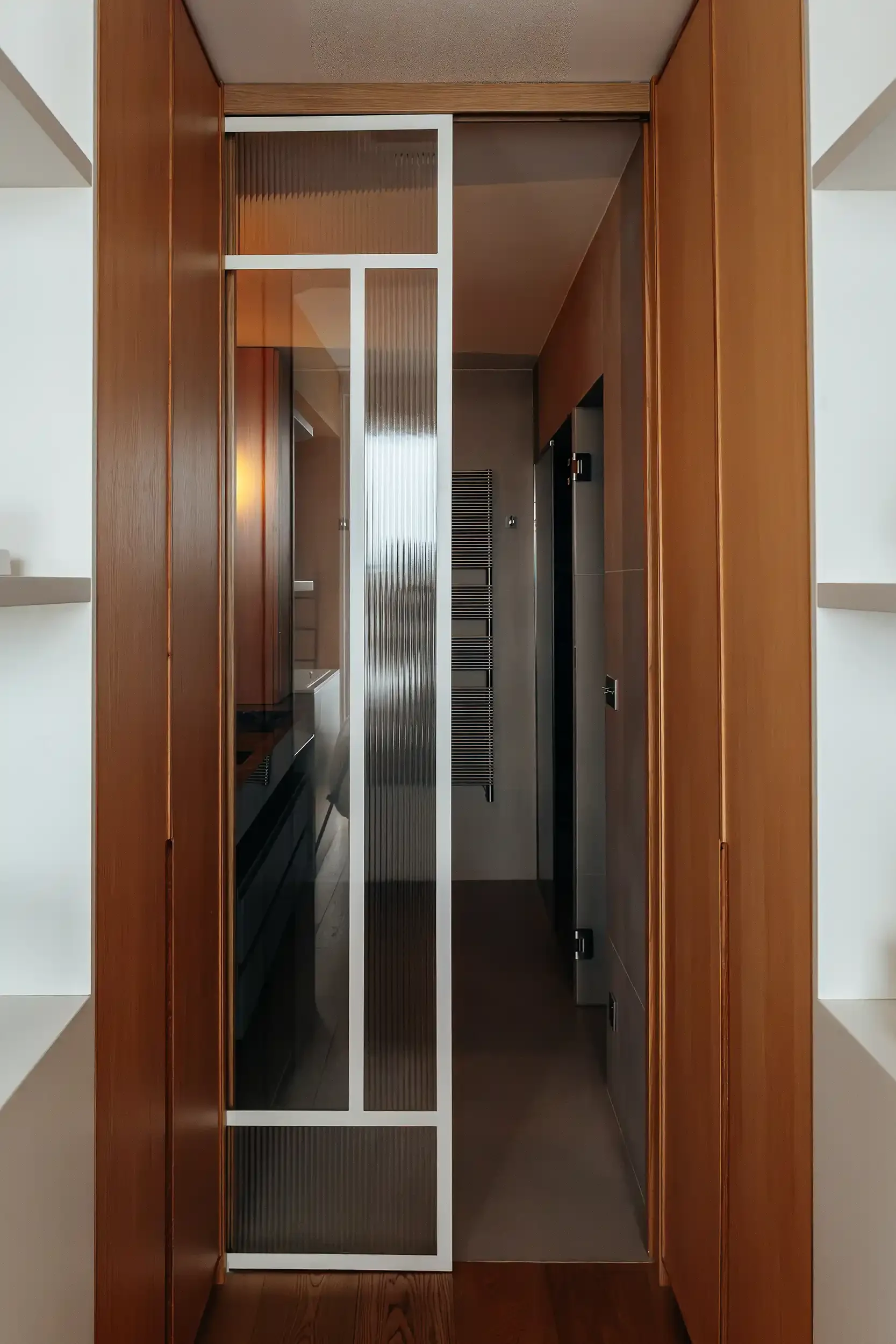 Porte coulissante en verre strié et cadre blanc séparant une chambre d'une salle de bain contemporaine.