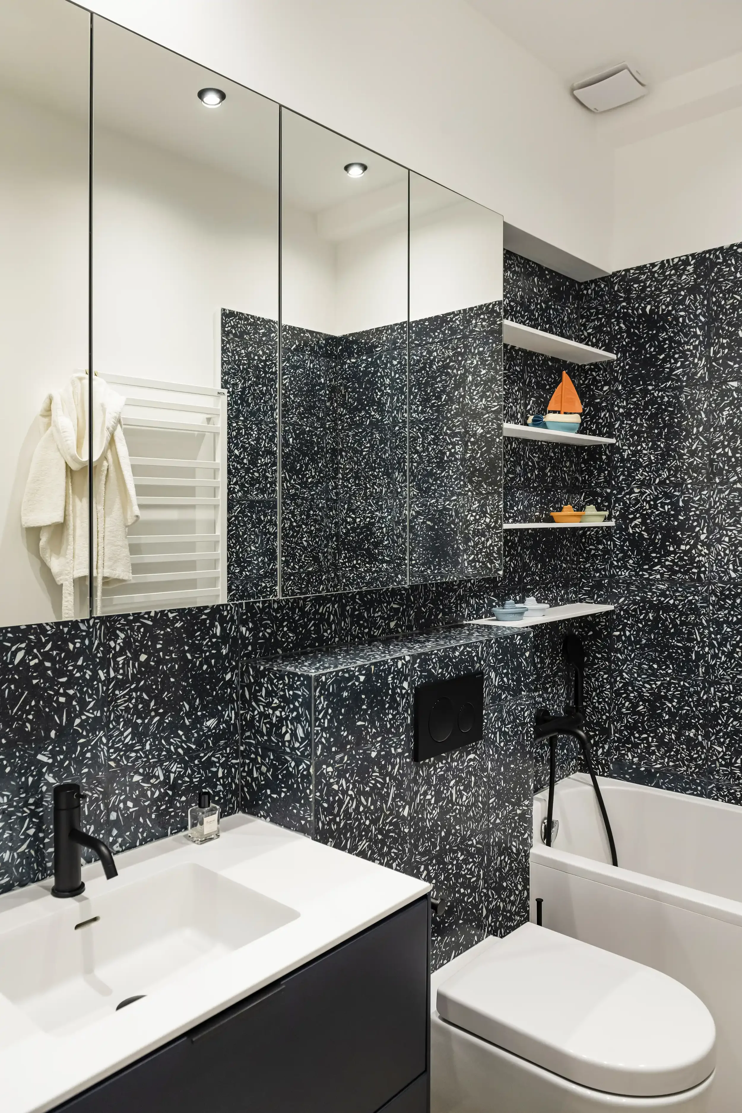 Salle de bain pour enfant avec carrelage effet terrazzo bleu, meuble vasque minimaliste et miroir rond