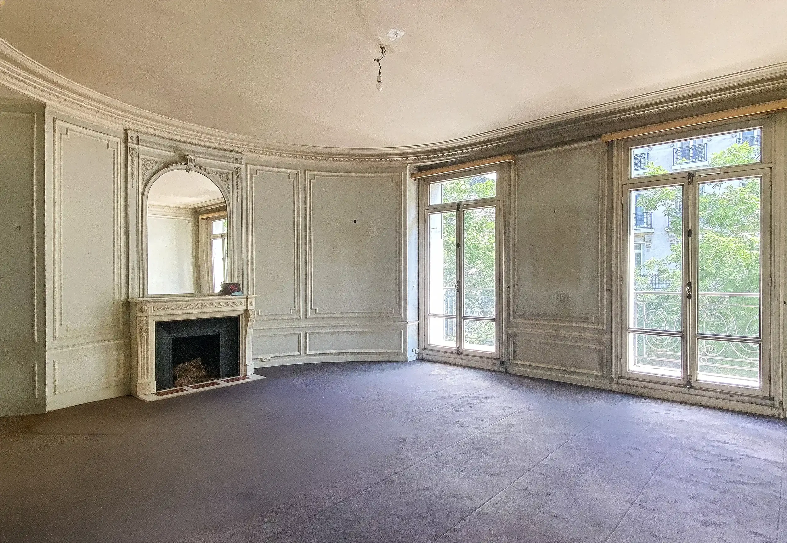 Salon spacieux en cours de rénovation avec moulures d'époque, grande cheminée en marbre et fenêtres coulissantes style Haussmannien à Paris.