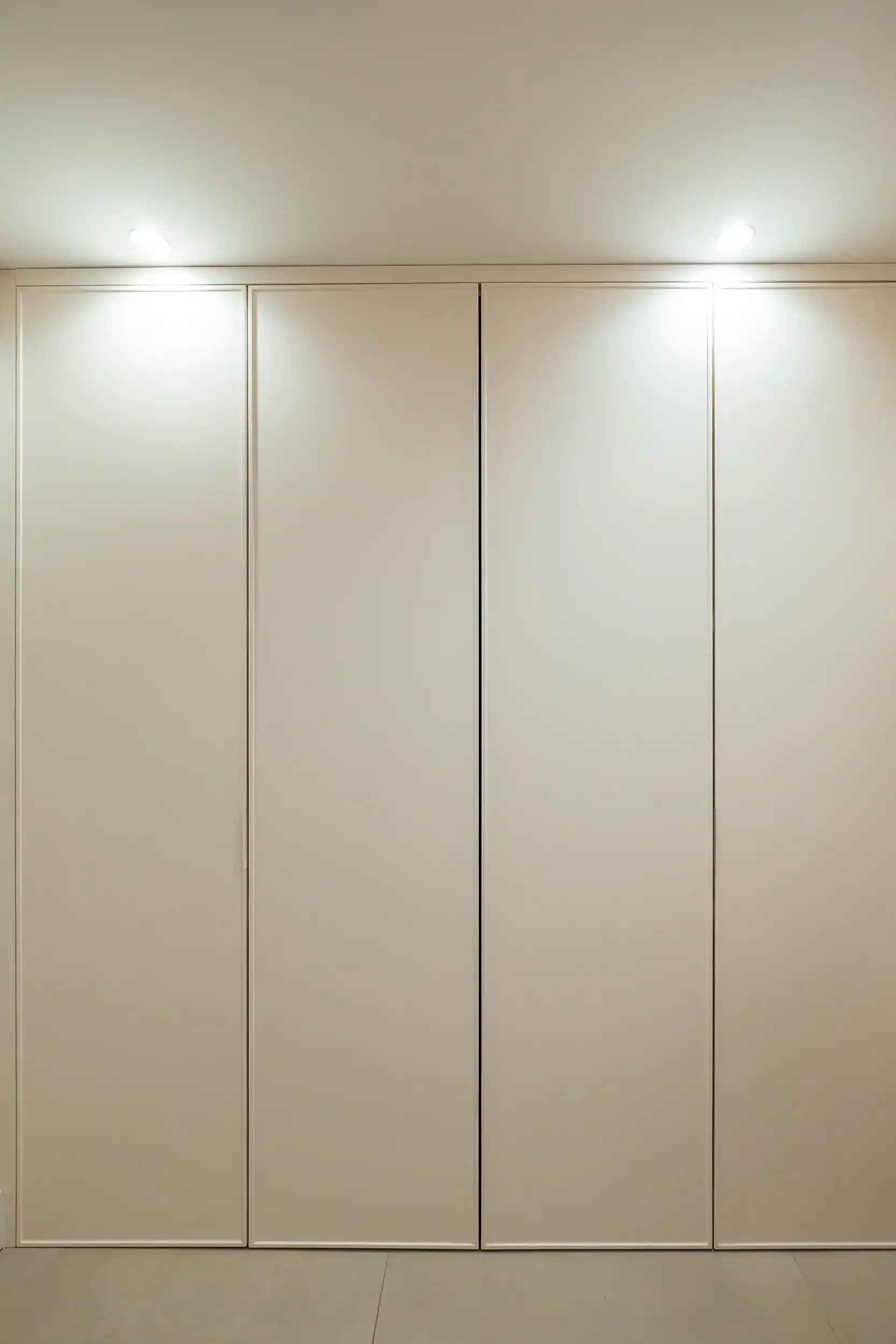 Façade de placard de buanderie minimaliste blanc cassé avec éclairage LED intégré au plafond.