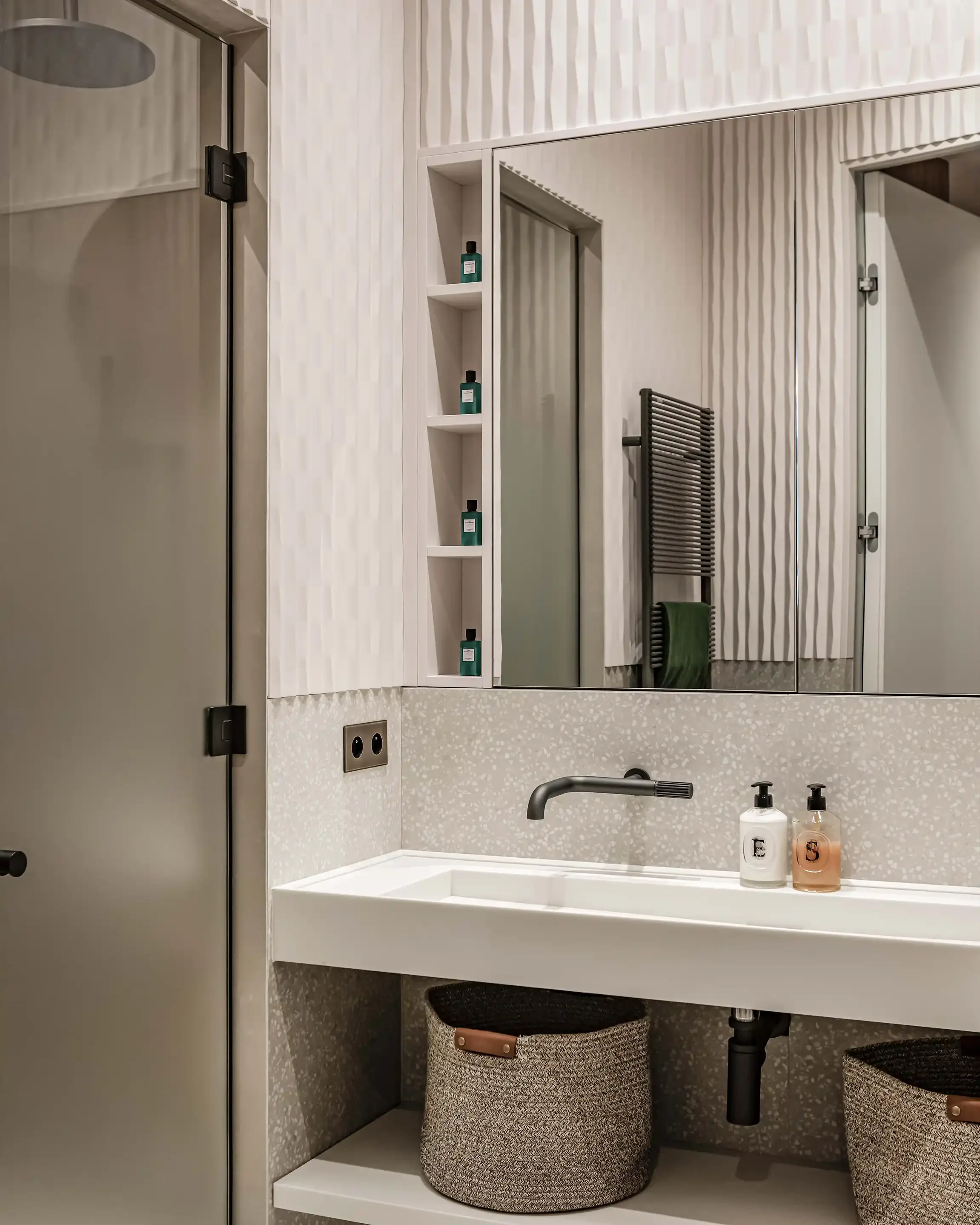 Meuble vasque blanc suspendu avec robinetterie noire encastrée et meuble miroir sur-mesure dans une salle de douche contemporaine.