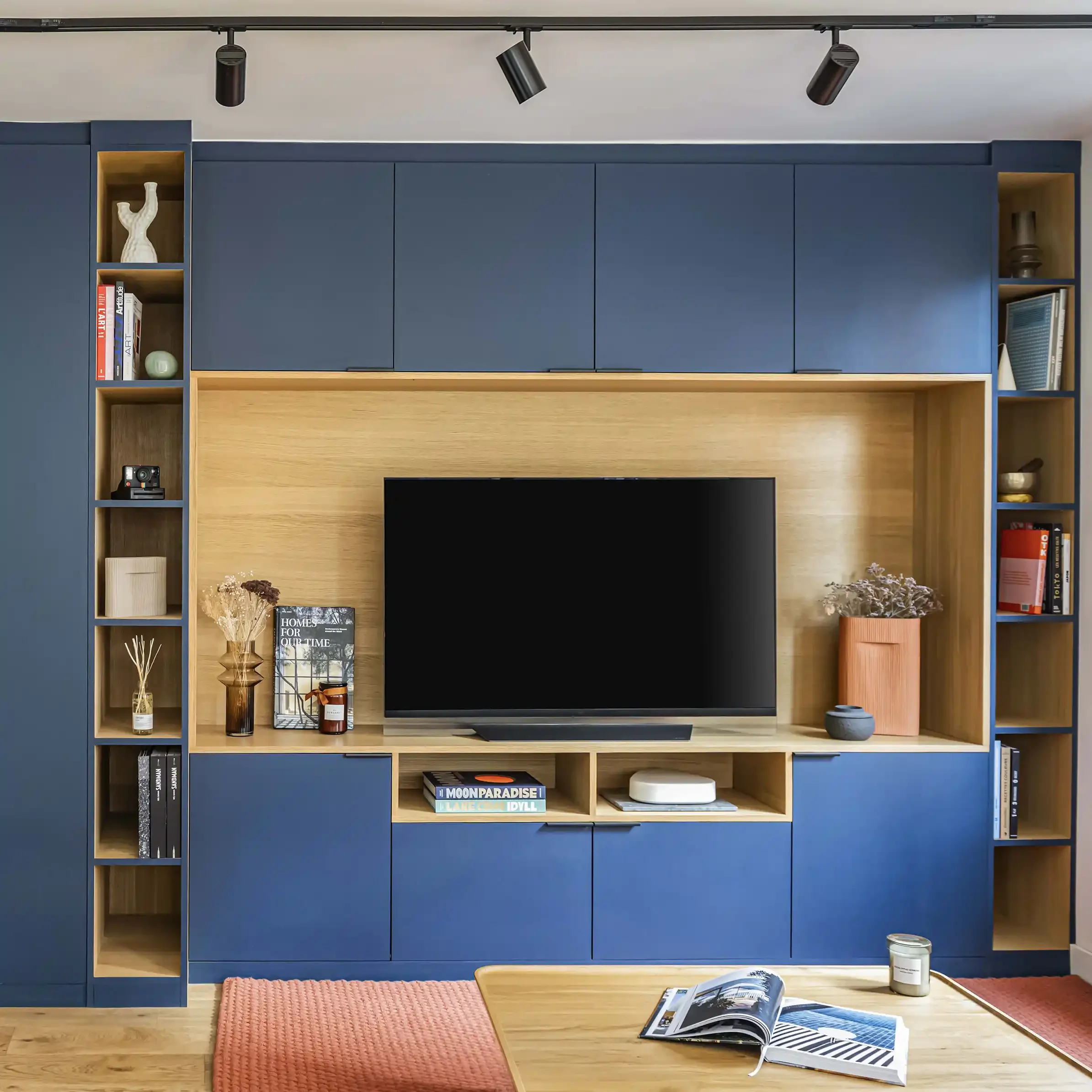 Salon contemporain avec grand agencement sur mesure bleu nuit incluant bibliothèque, rangements et coin TV.