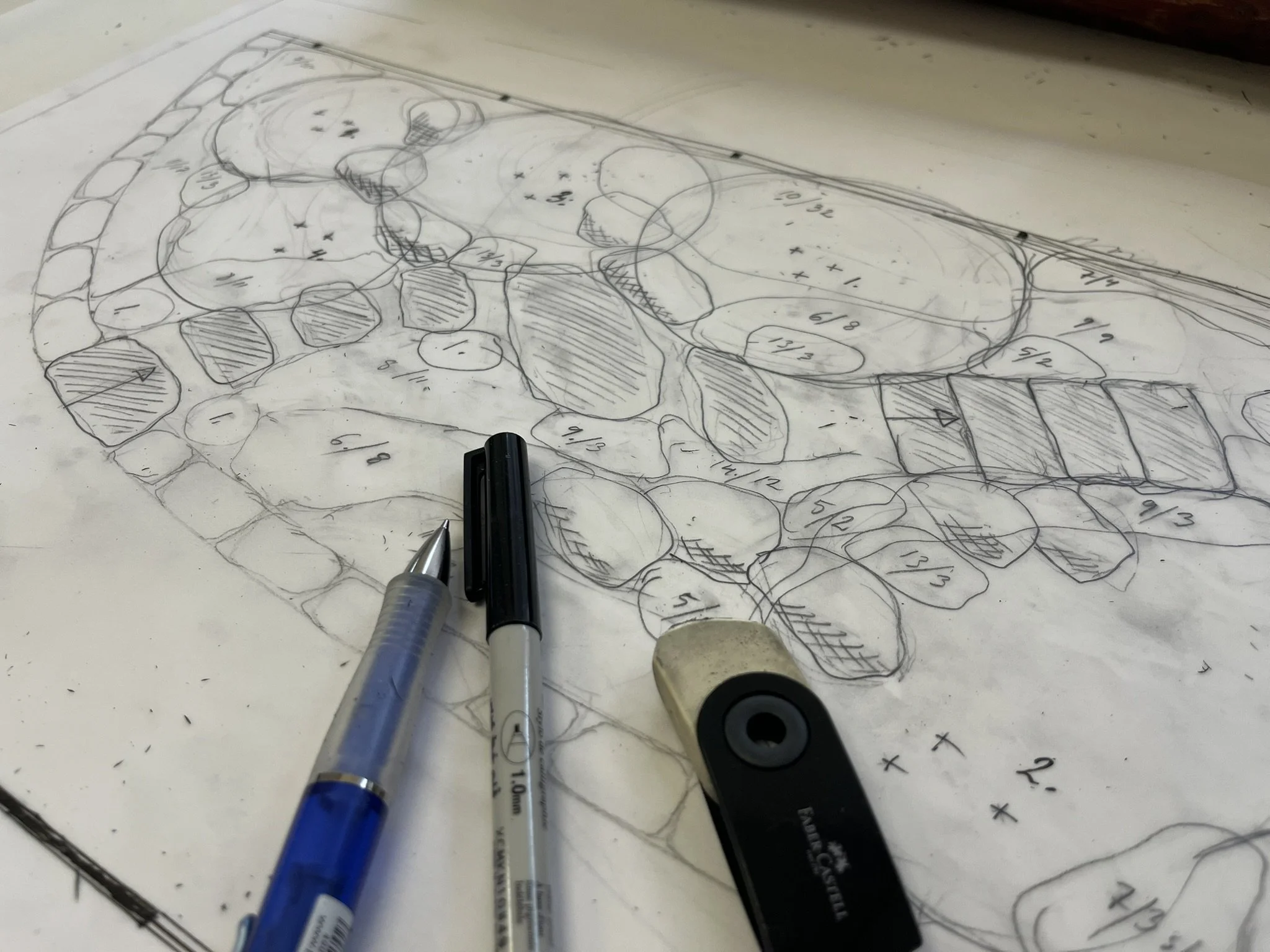 Arkitektoniskt ritningspapper med skala och nummer, penna, penna med svart bläck, USB-minne och ett spaltningsverktyg ligger på ritningen.