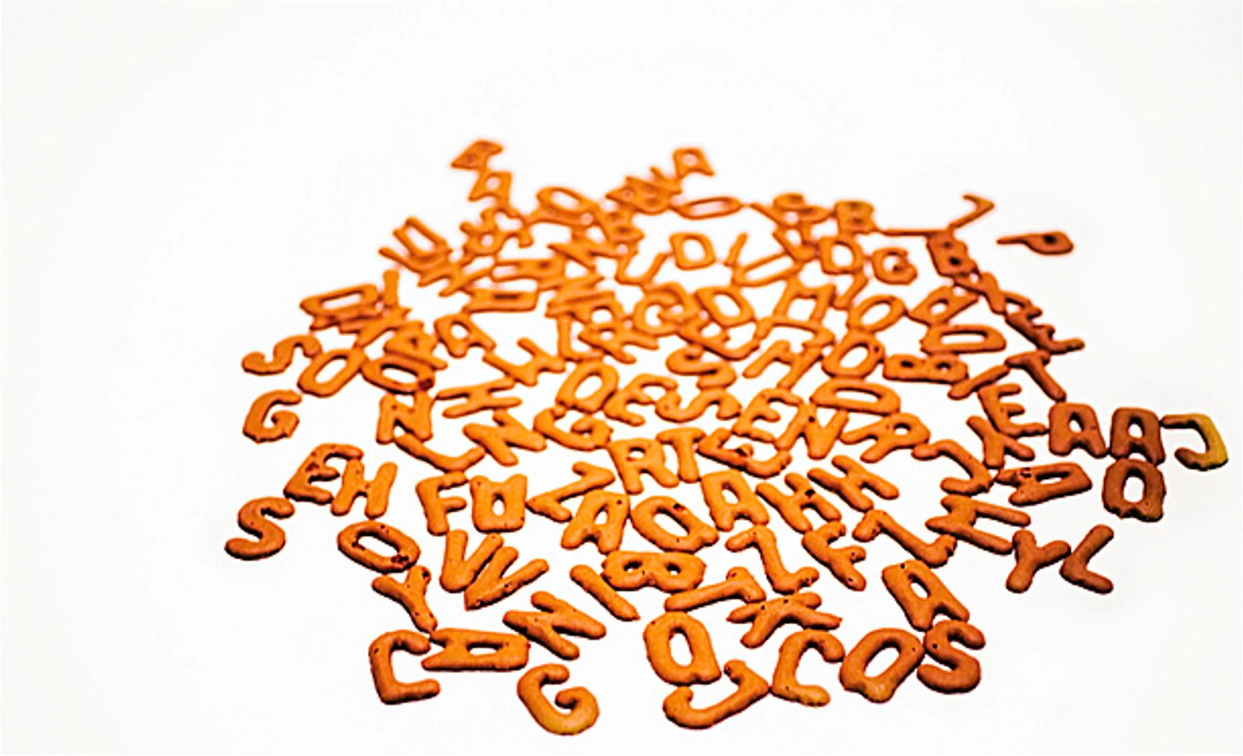 Orange letter-shaped pasta scattered on a white surface.