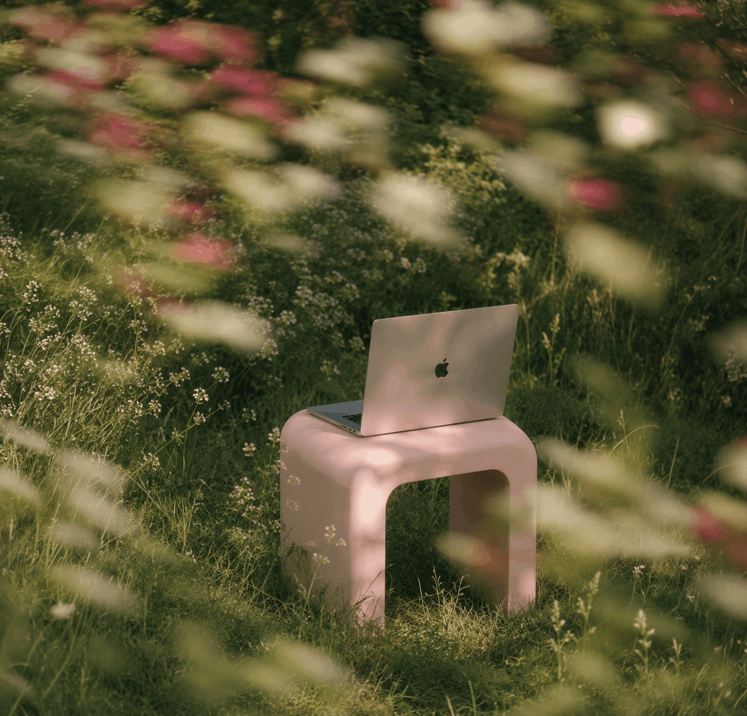 MacBook on a minimalist stool surrounded by wildflowers, symbolizing a calm and intentional Squarespace website design workspace.