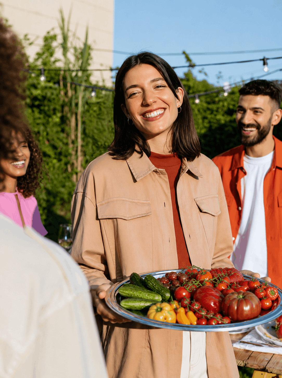 AI-generated lifestyle image of friends gathering outdoors with a platter of fresh tomatoes, cucumbers, and peppers, celebrating fresh produce through a summer food campaign.
