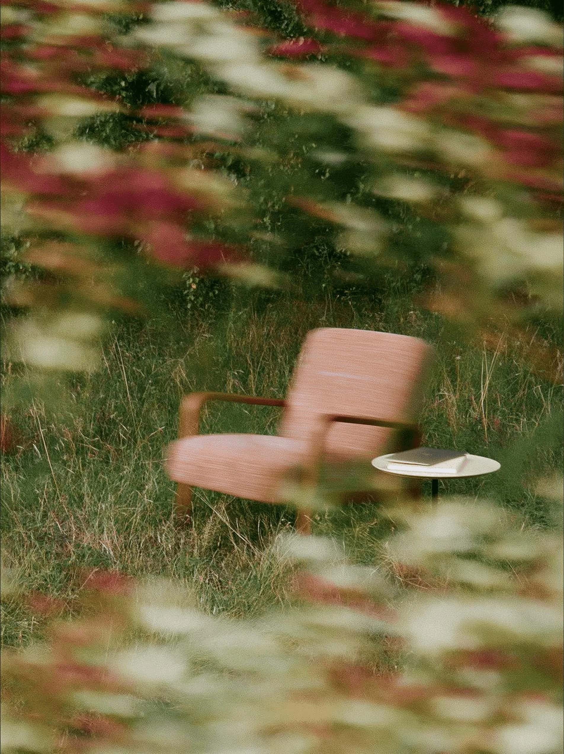 Minimal lounge chair and side table in a grassy meadow, reflecting the calm and intentional approach to brand identity and website design.
