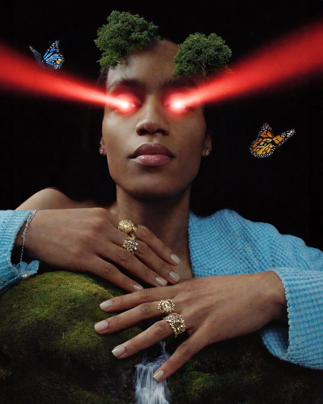 A woman with glowing red laser eyes, dark skin, wearing a blue sweater, with trees and butterflies on her head, surrounded by a forest scene with moss and a small waterfall.