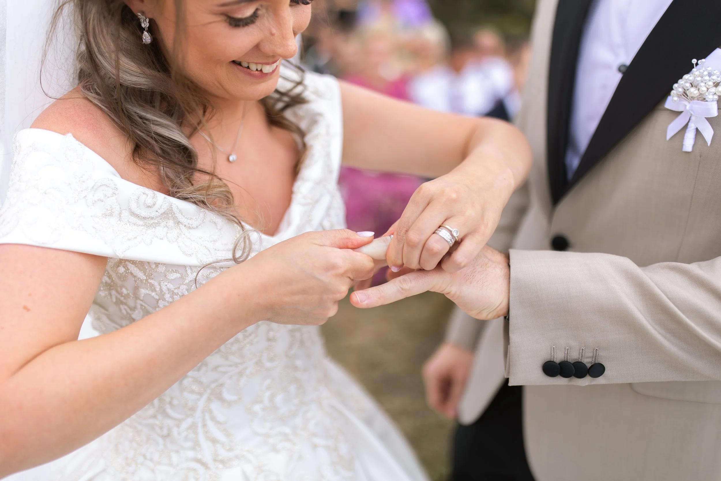 A bride placing a wedding ring on the groom's finger during a wedding ceremony.