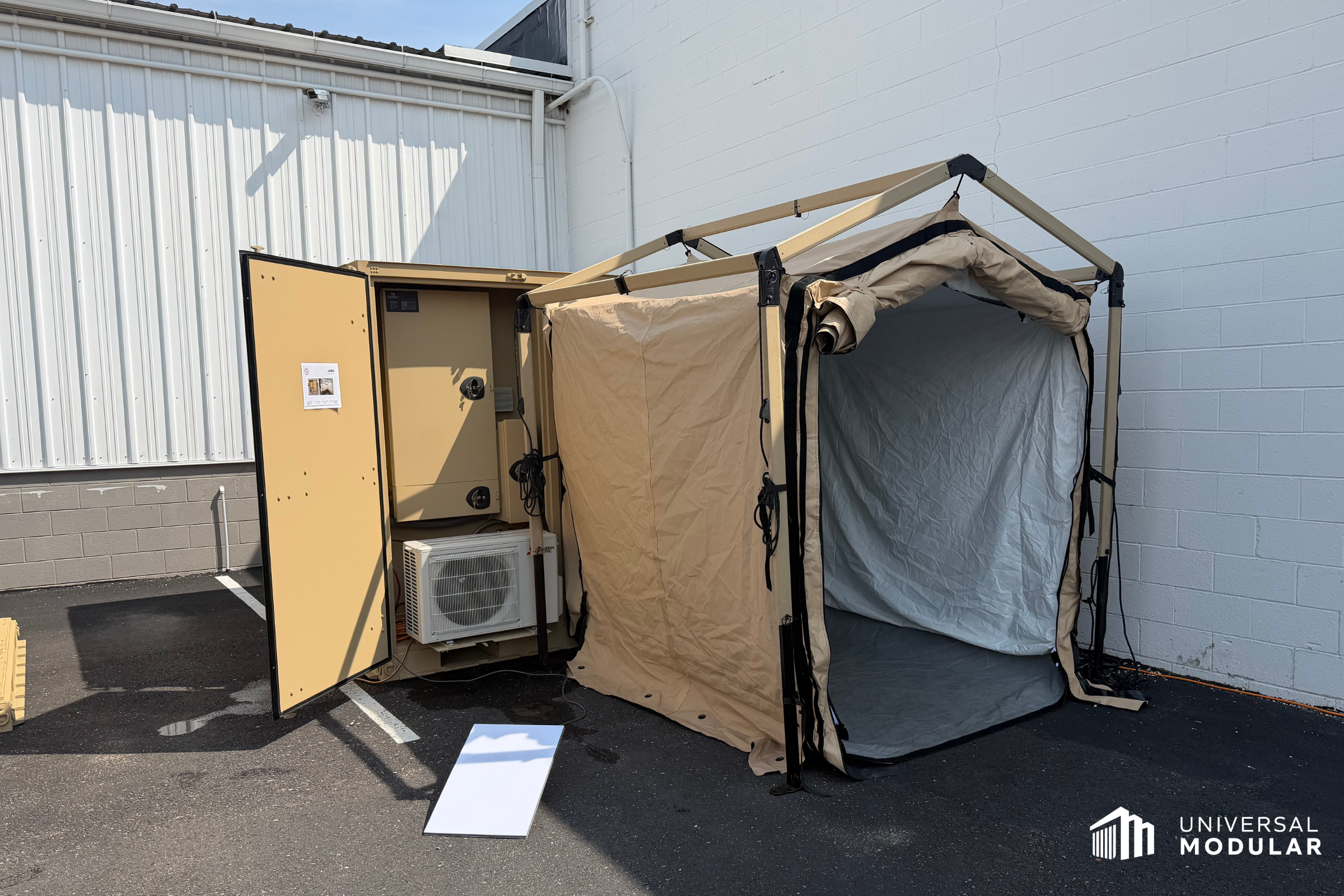 image of deployable modular scif for temporary operations sitting on asphalt in front of cement block and metal buildings outside