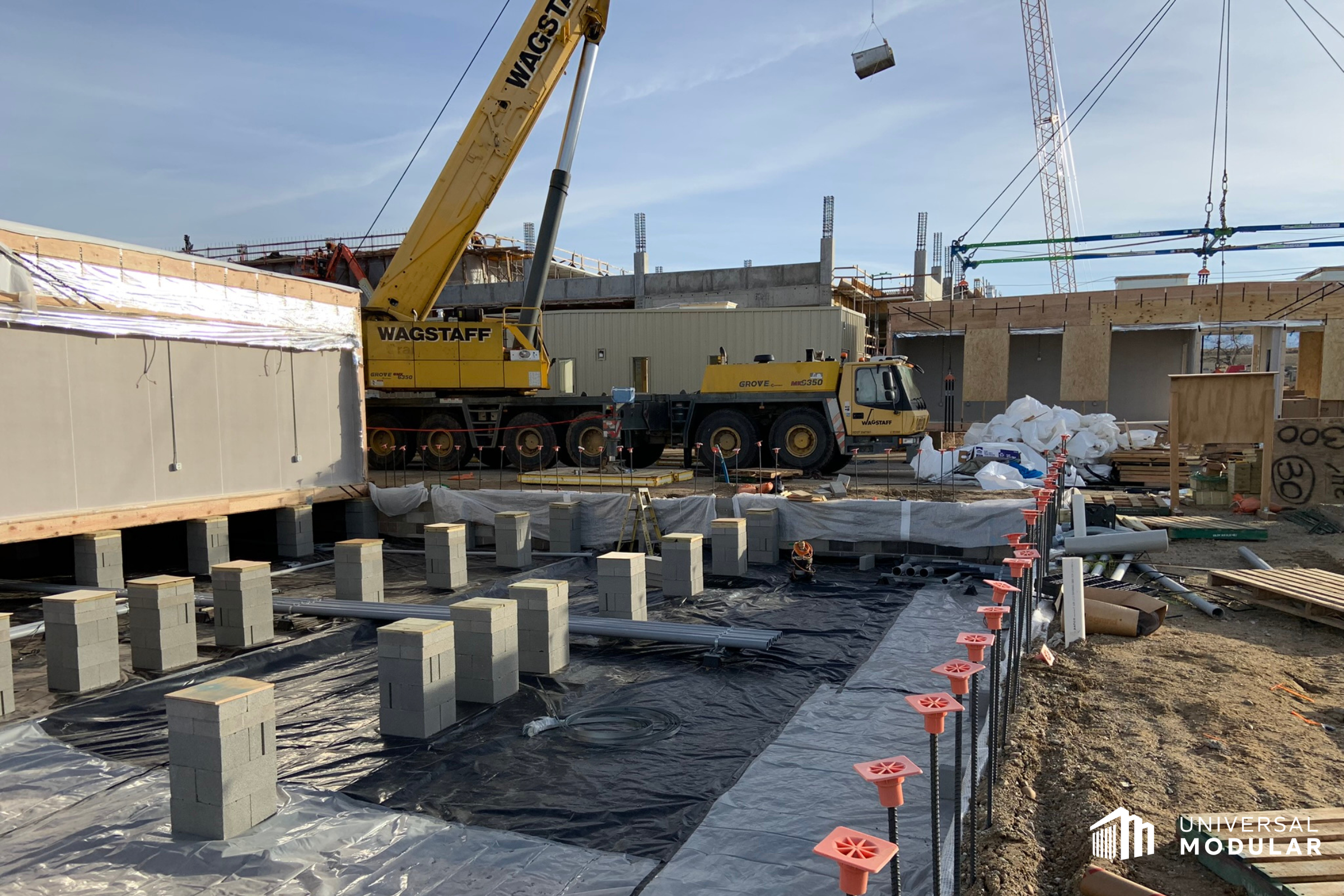 photo of outdoor modular building construction site where pit-set foundation is ready for modular building to be installed with crane in the background