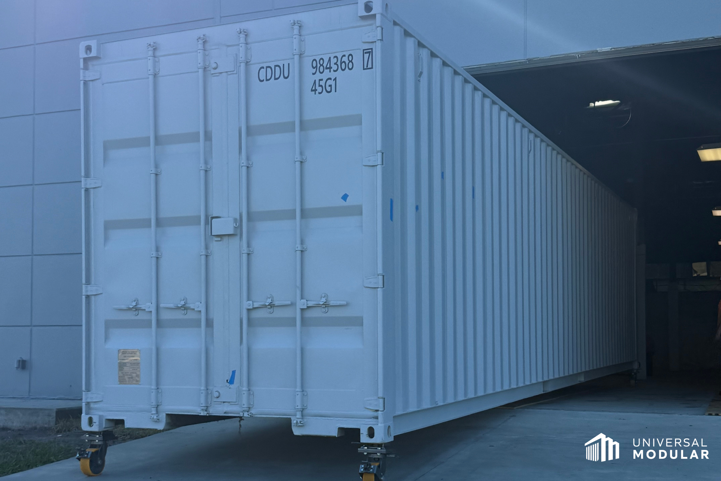 white container scif, or scif in a box, on wheels is halfway loaded into a warehouse door