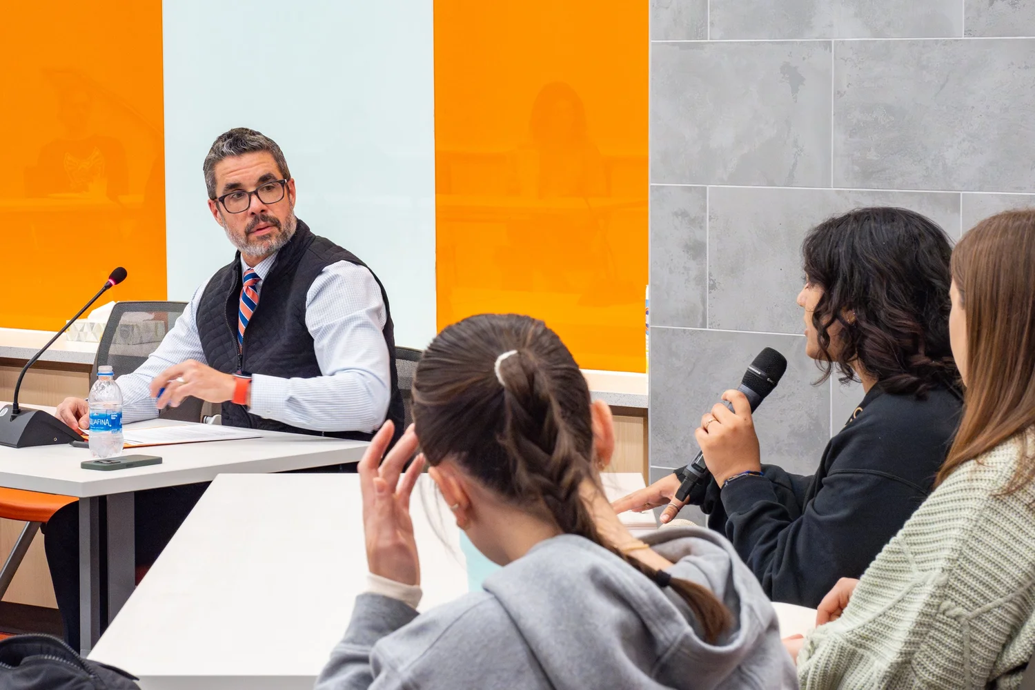 Student asks a question to a panel moderator in a modern classroom — university event photographer, Syracuse NY.
