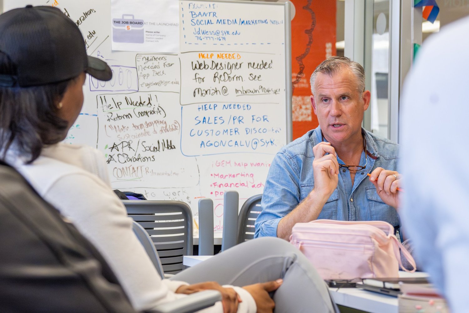 Mentor advising a student beside a whiteboard of job-board notes — startup coaching session photography.