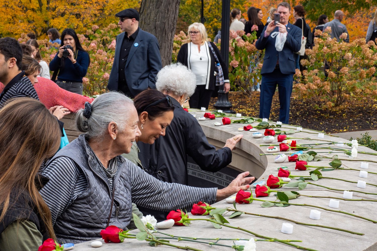Community remembrance ceremony at a Syracuse memorial with roses and candles — candid event photography.