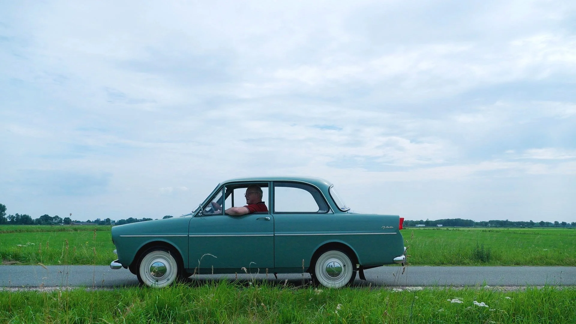 Vintage auto op landweg met groene velden op achtergrond