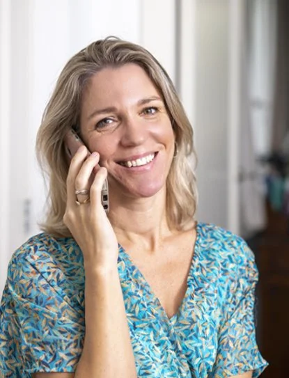 Vrouw glimlacht terwijl ze met een mobiele telefoon belt.