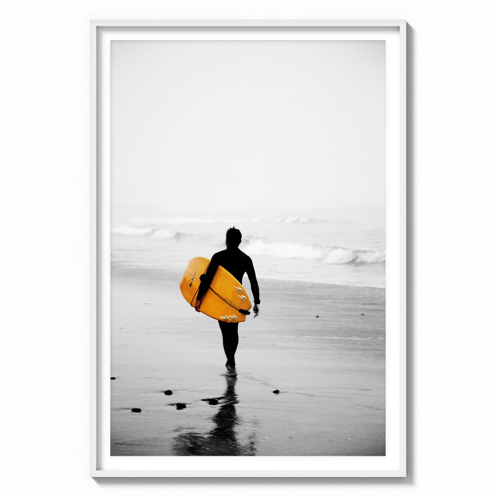 This stunning wall art features a lone surfer, poised with a vibrant yellow surfboard, heading towards the misty ocean waves in a white wood frame.