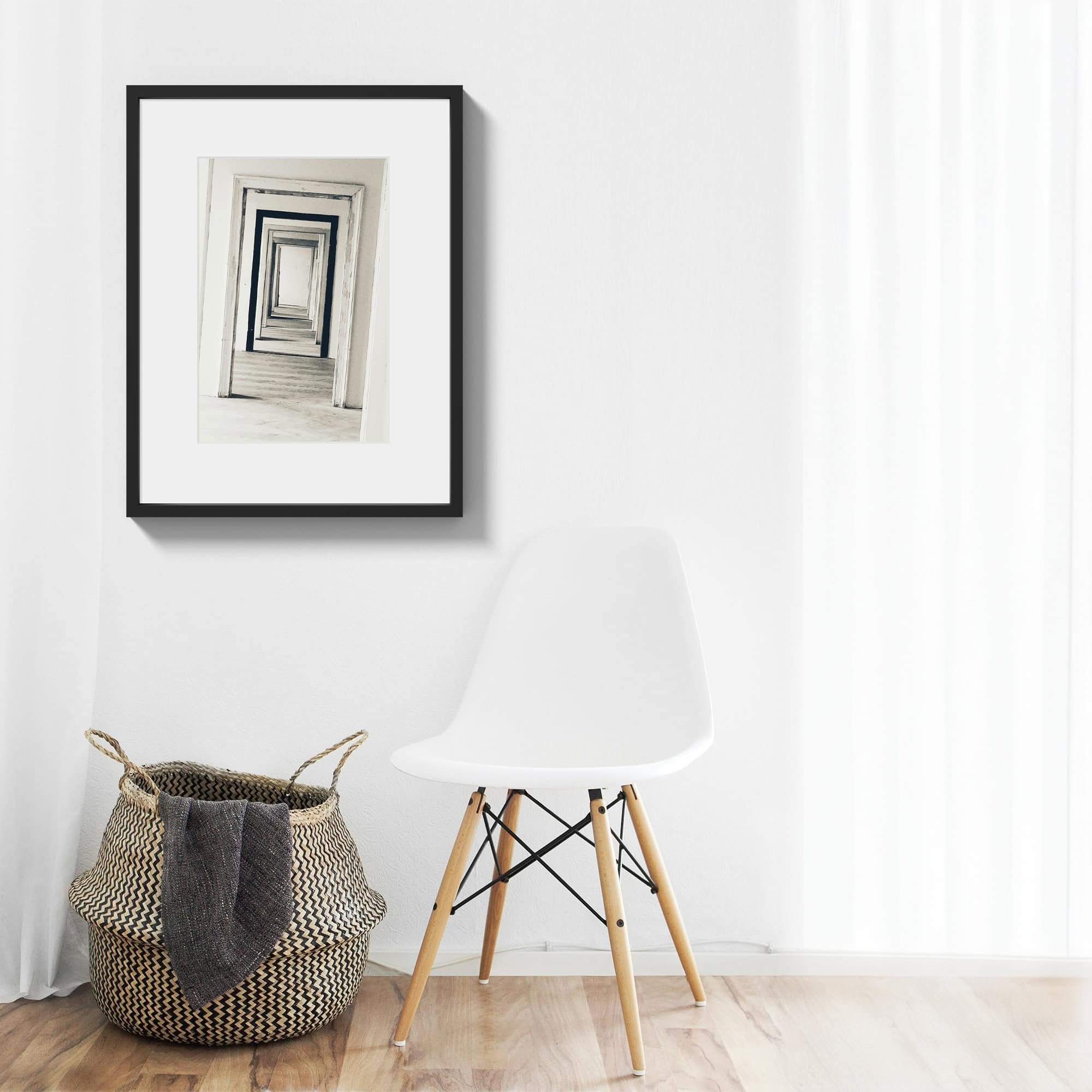 A black and white print of multiple doorways hung in an entry way with wood frame.